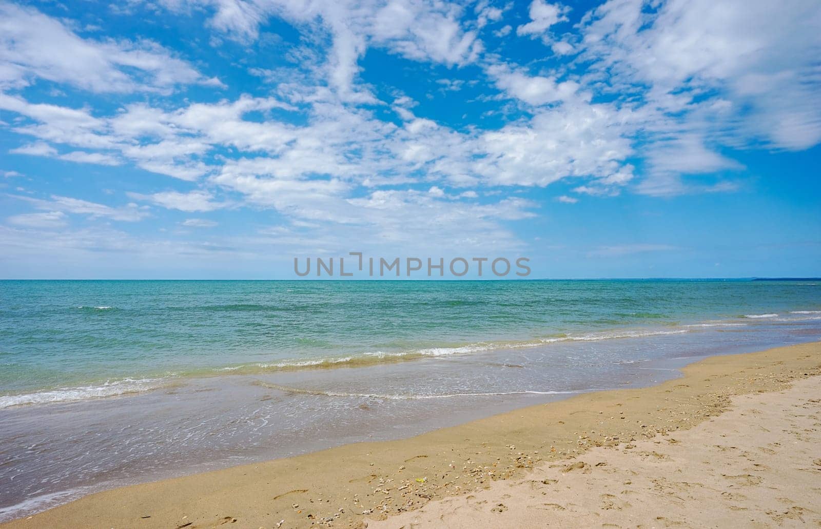 Blue cloudy sky and calm blue waters of beautiful Hervey Bay on a sunny day at Pialba on the sandy beach along the shoreline.