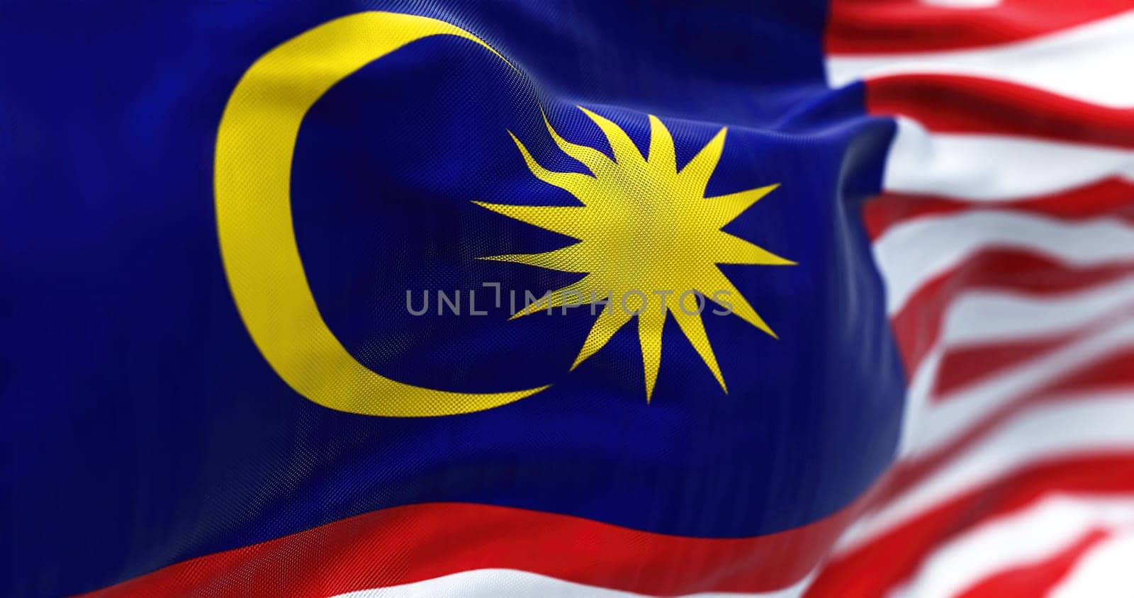 Close-up view of the Malaysia national flag waving in the wind. Malaysia is a federal state in Southeast Asia. Fabric textured background. Selective focus