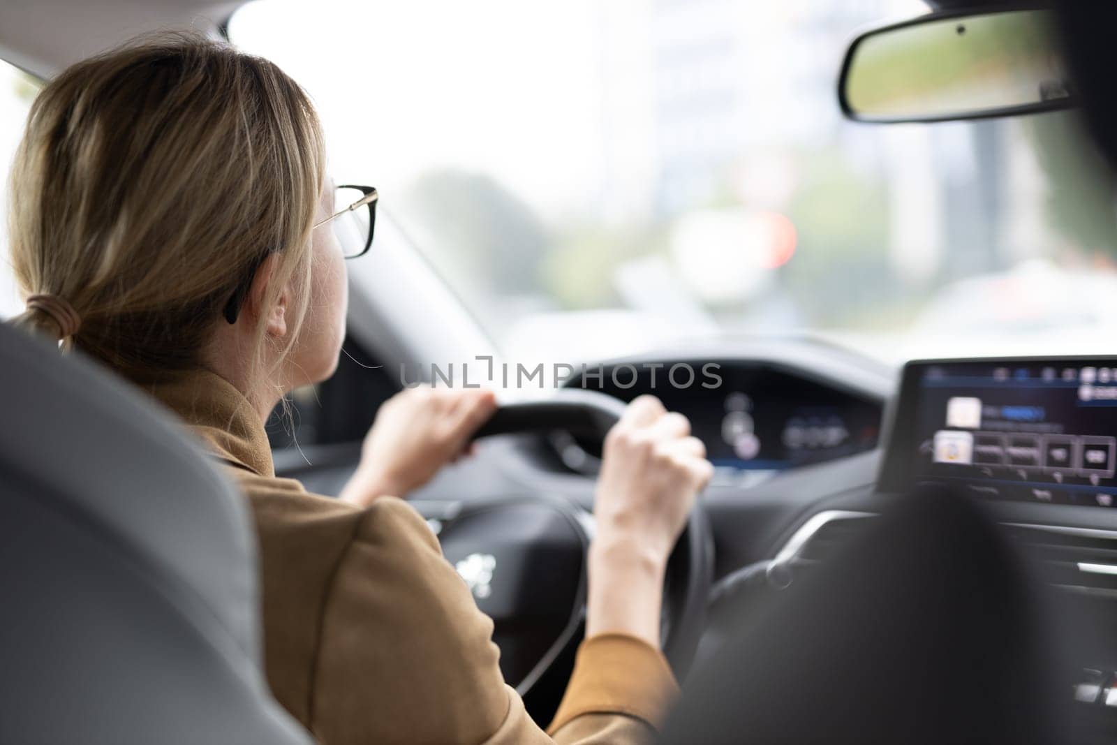 Business woman driving a car to work. Female driver steering car on the road.