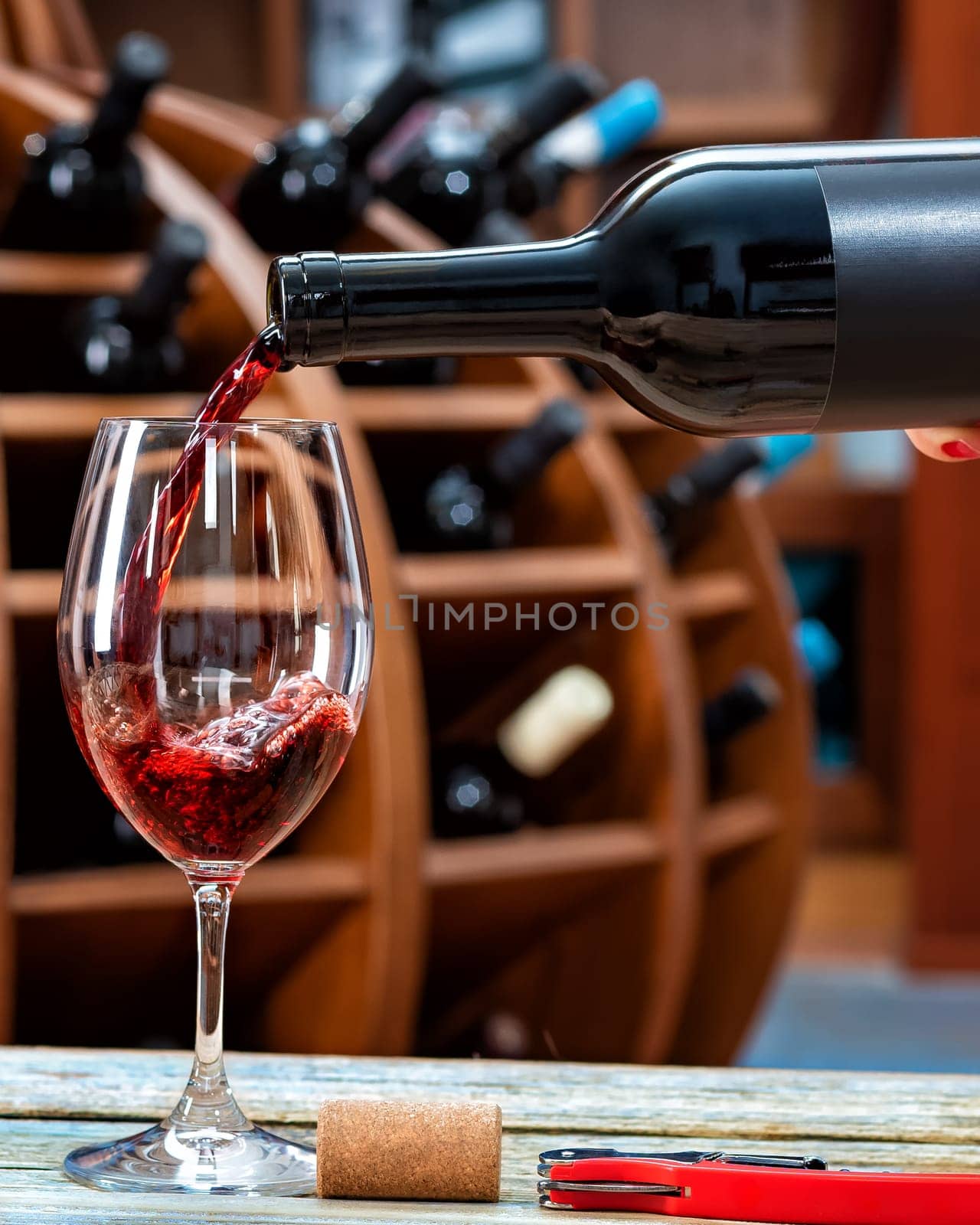 Winery. Pouring red wine from the bottle into the wine glass for tasting, on a rustic wooden table. Beverage, alcohol.