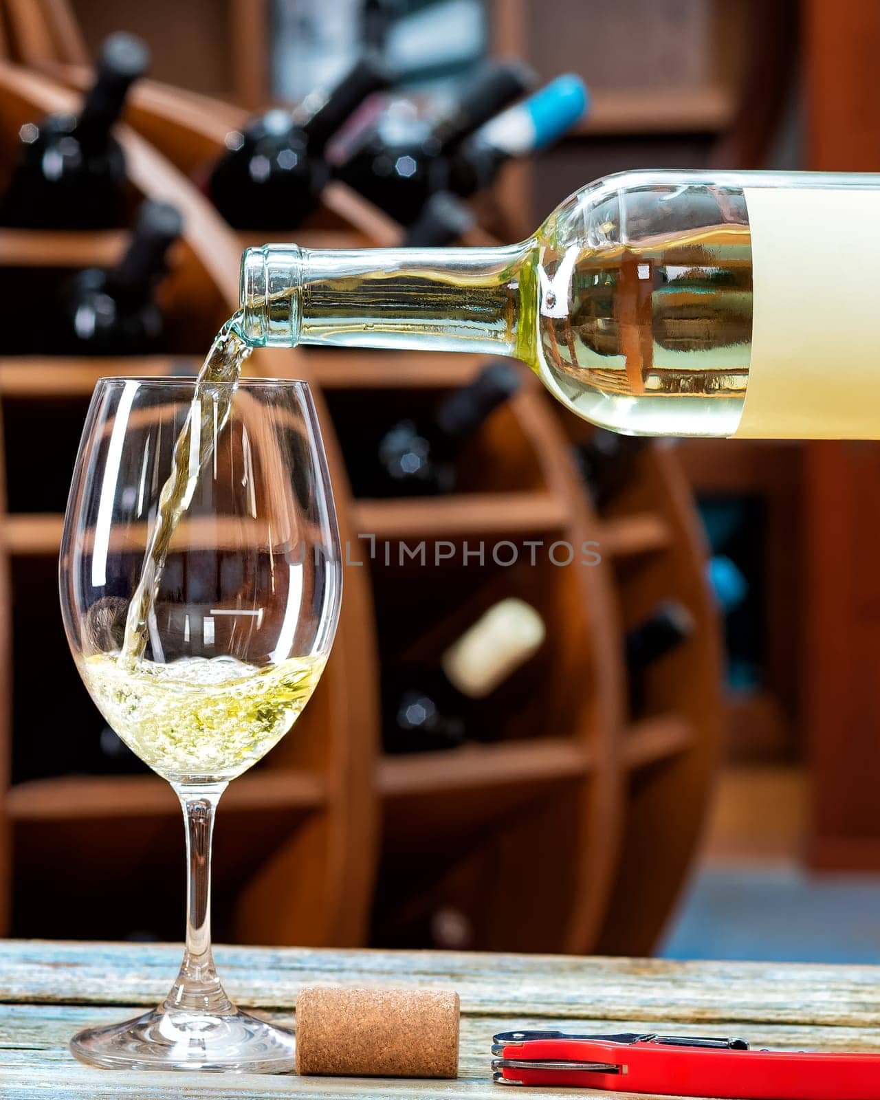 Winery. Pouring white wine from the bottle into the wine glass for tasting, on a rustic wooden table. Beverage, alcohol.