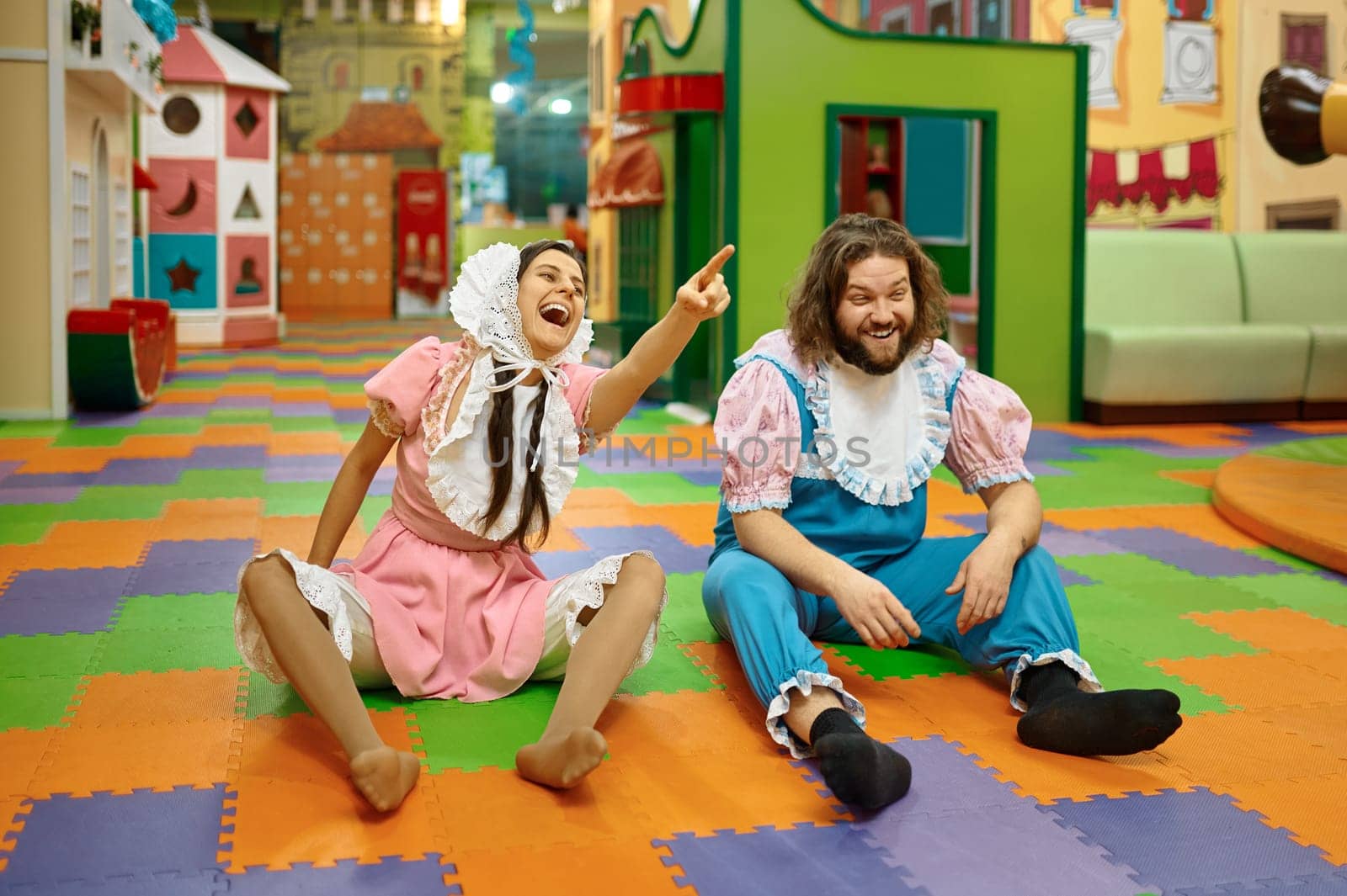 Funny man and woman wearing like newborn babies sitting on playroom floor