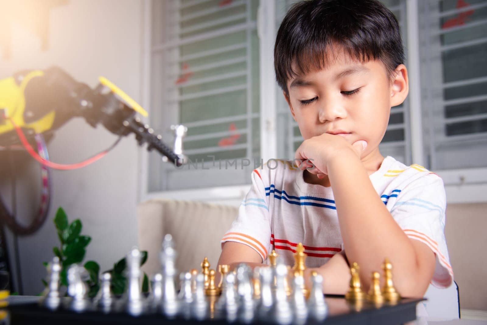 Asian little boy thinking and wait robot arm playing chess, STEM education E-learning, Funny children learning successful getting a lesson control robot arm game, Technology science education concept