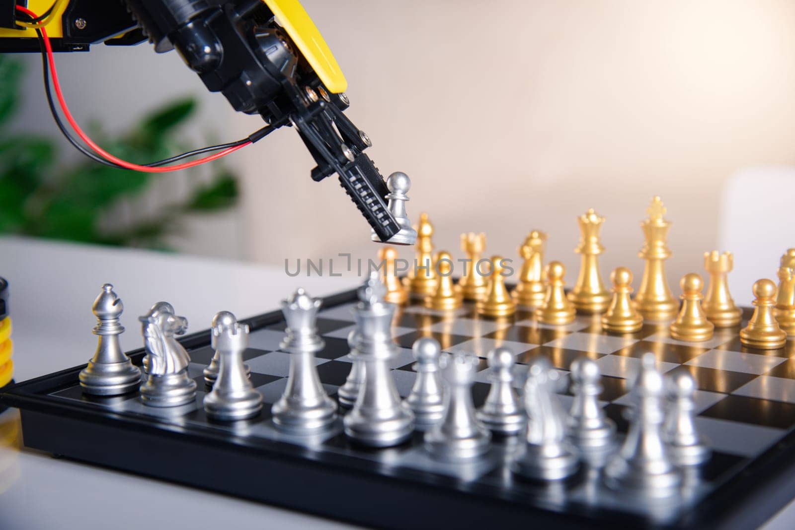 Closeup yellow robot arm playing move chess on chessboard, STEM education E-learning, Technology science robot education concept
