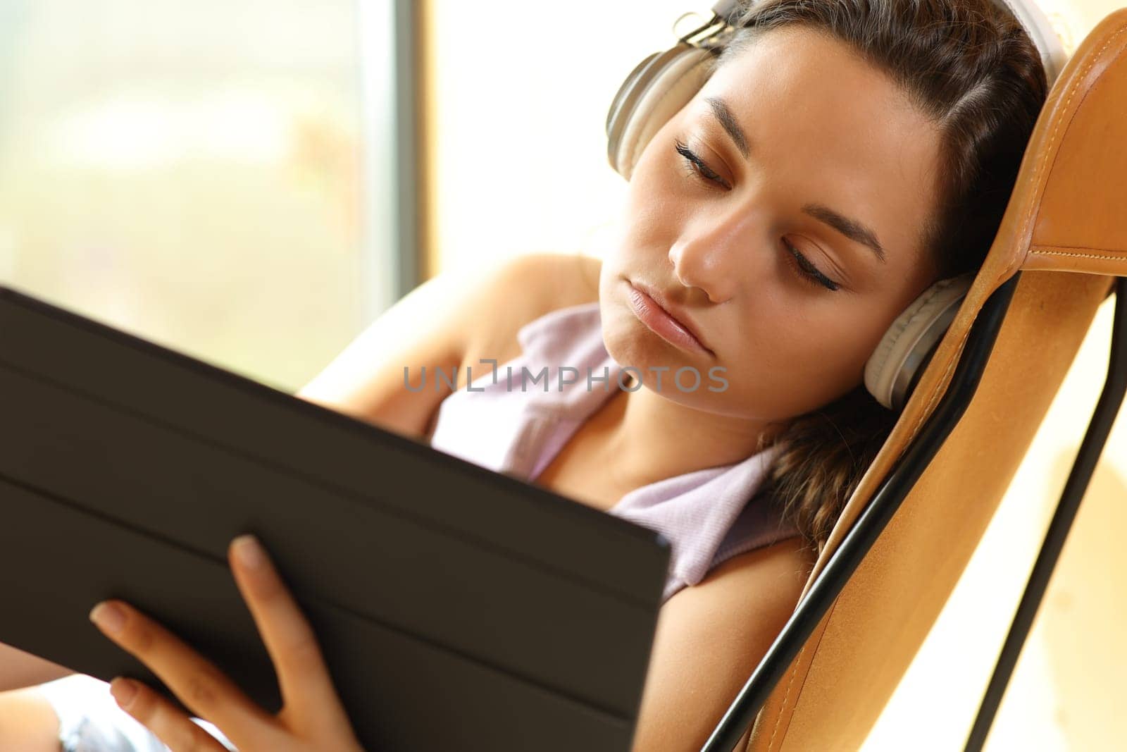 Bored woman watching videos on tablet sitting at home