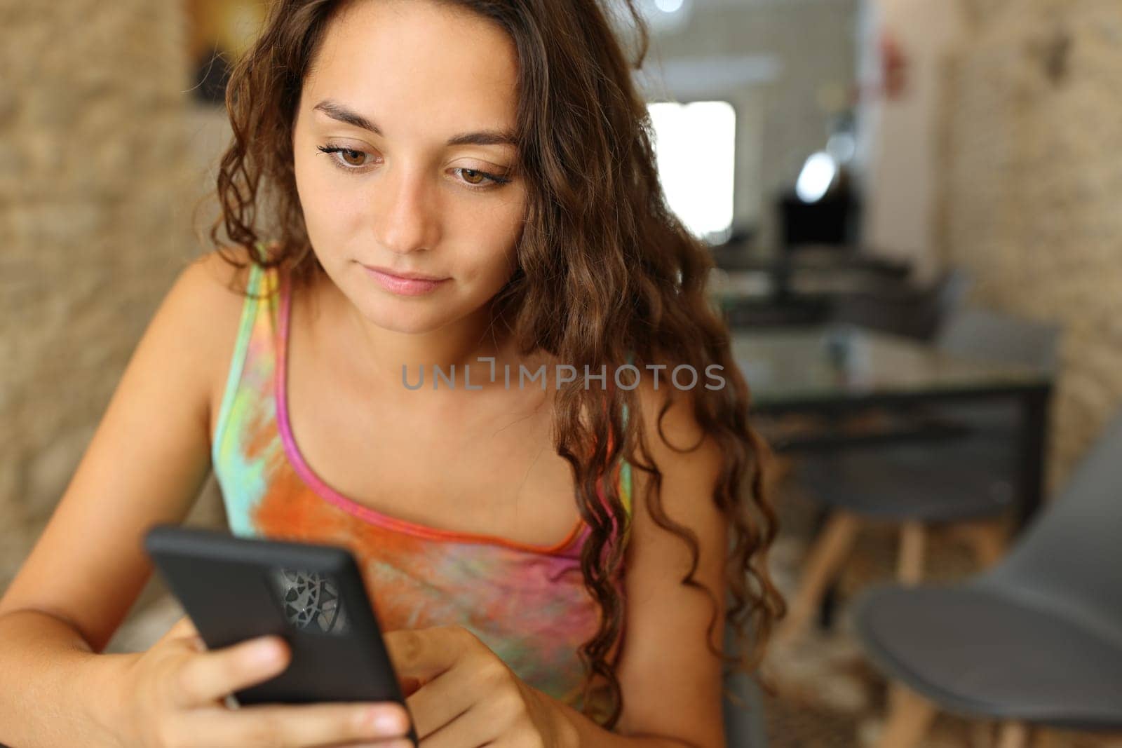 Serious woman using smart phone sitting in a restaurant