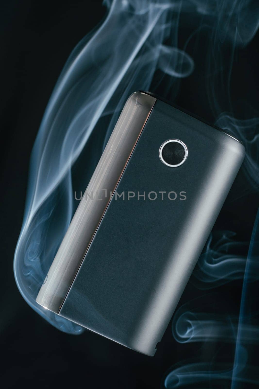 Black new GLO heating smoking device floats in puffs of white blue neon smoke. Modern electronic cigarettes