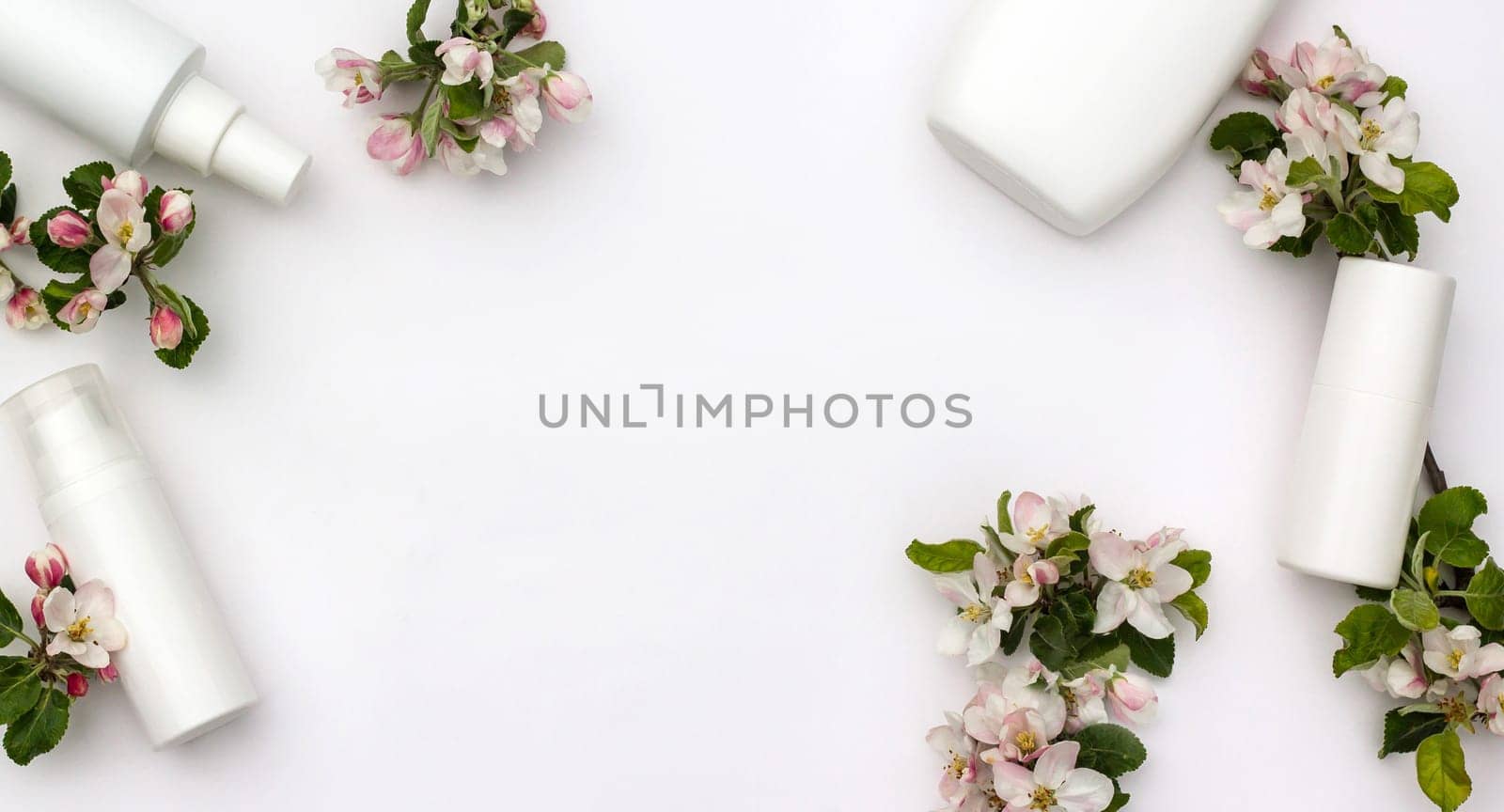 White cosmetic bottles with pear flowers on a white background. Natural organic cosmetics concept. Banner