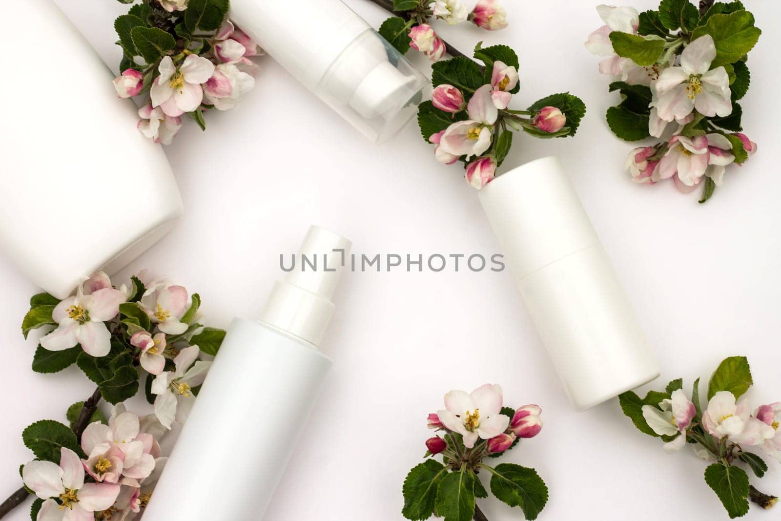 White cosmetic bottles with pear flowers on a white background. Natural organic cosmetics concept.