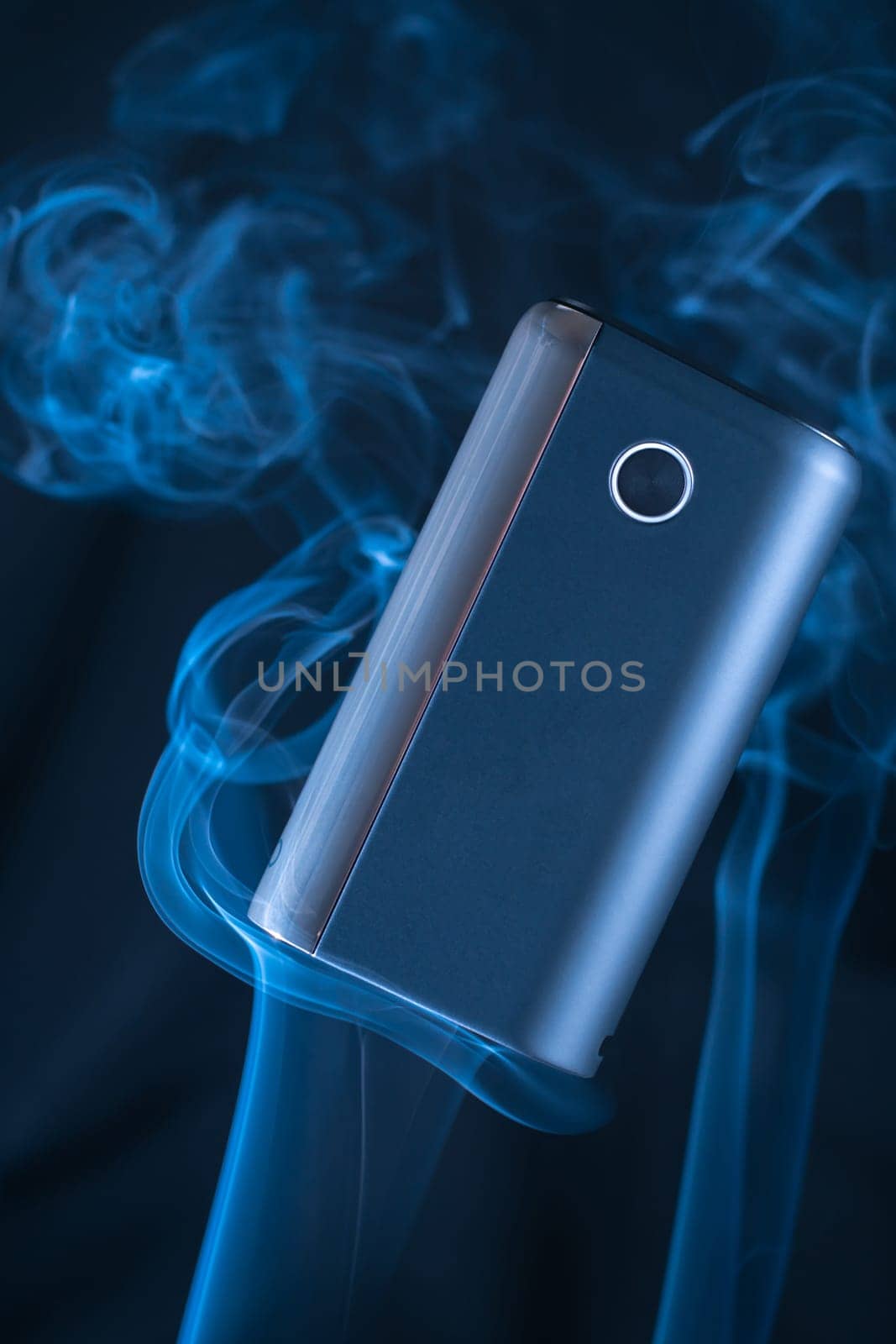 Black new GLO heating smoking device floats in puffs of white blue neon smoke. Modern electronic cigarettes