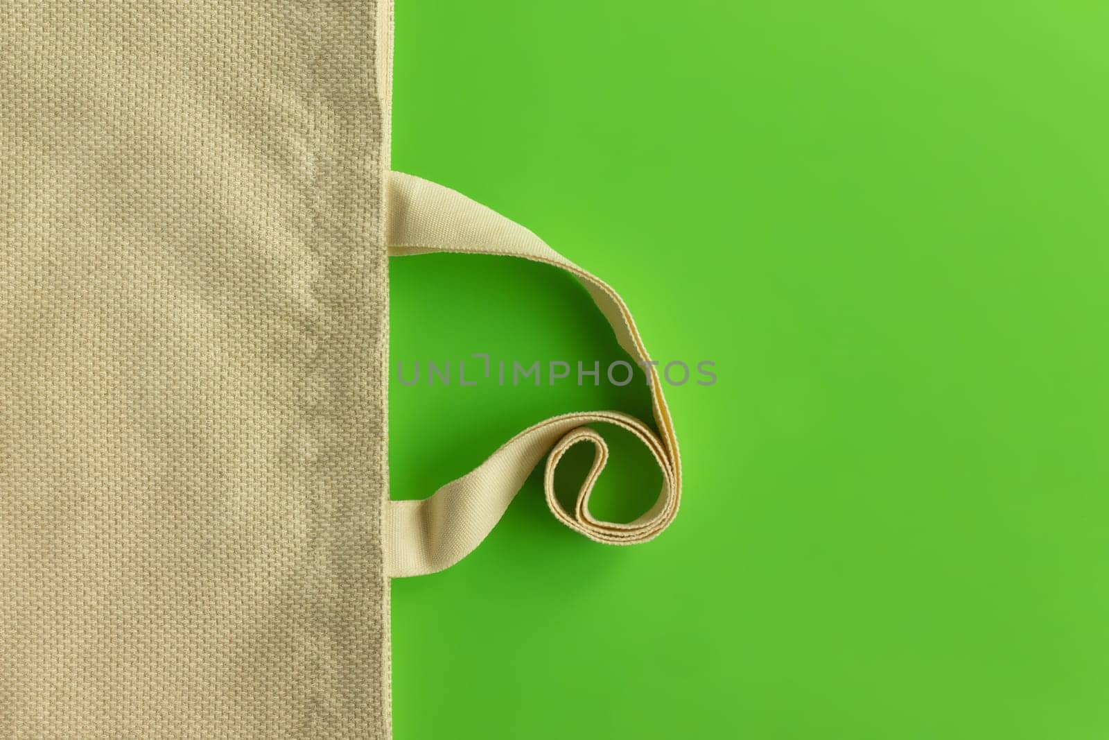 Fabric cotton shopping bag on a green background. Zero waste and ecological concept. Top view, copy space.