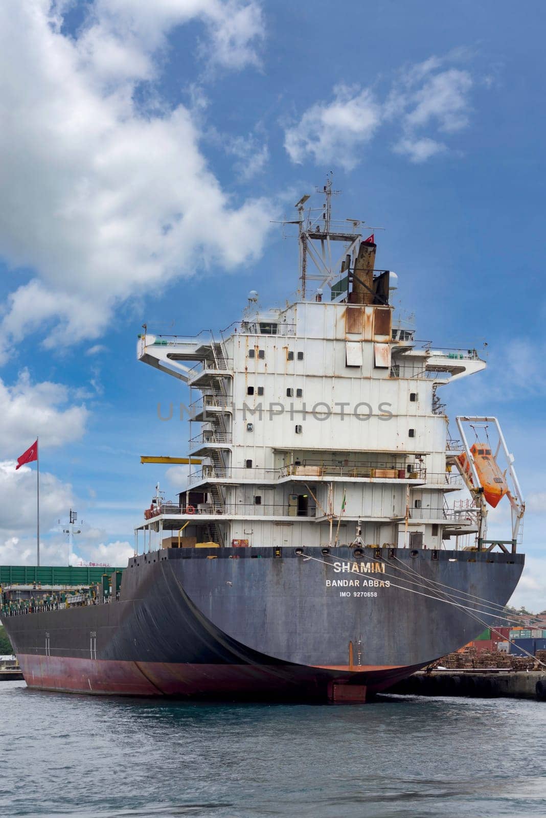 Bandar Abbas, container ship, docked at the shipyard of the Port of Haydarpasha with Turkish flag in the background, at Kadikoy district, Istanbul, Turkey
