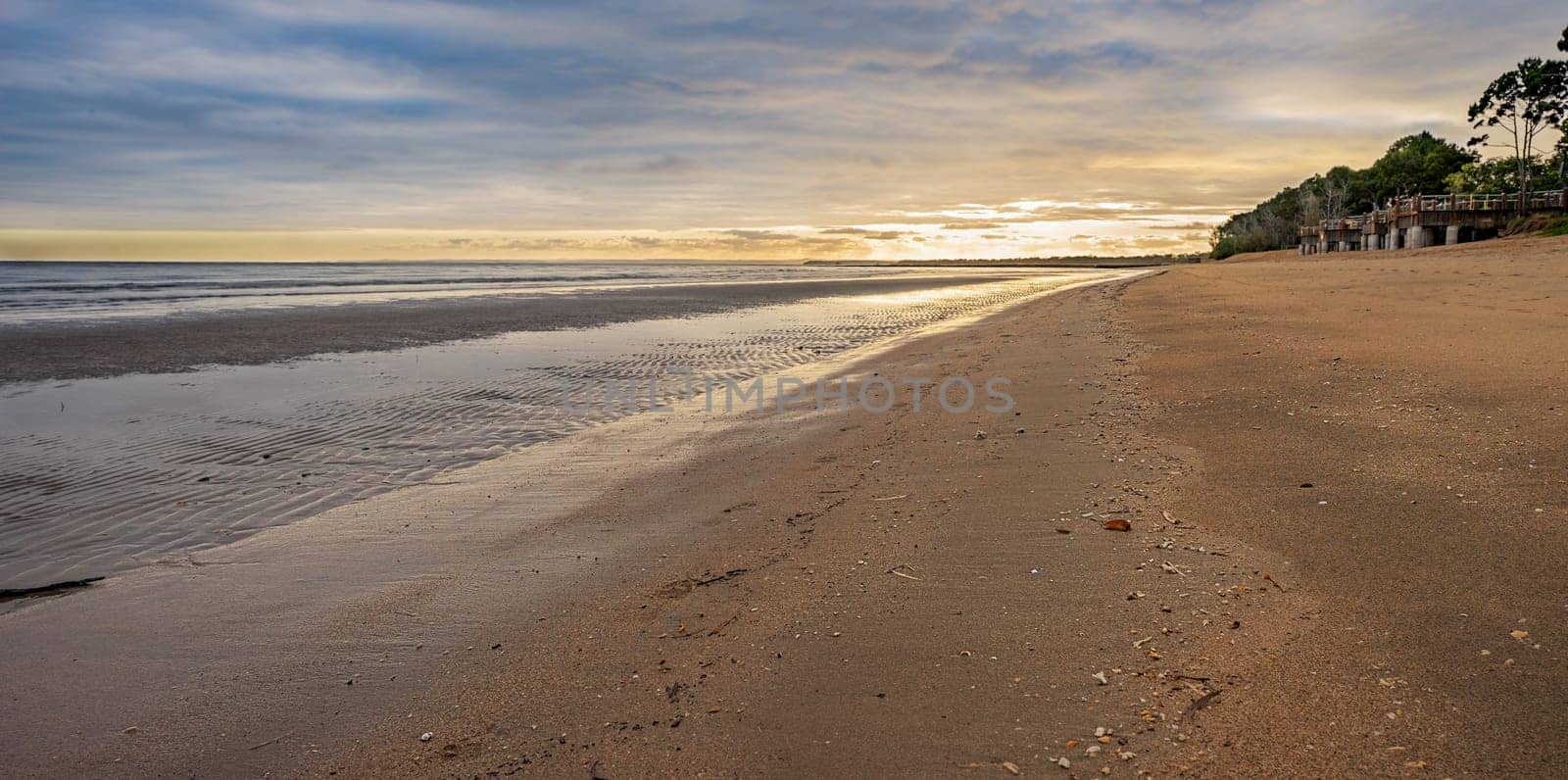 Sunrise on a stormy morning over Pialba, Hervey Bay Queensland, at low tide showing a sandy foreshore. This is a very popular tourist destination.