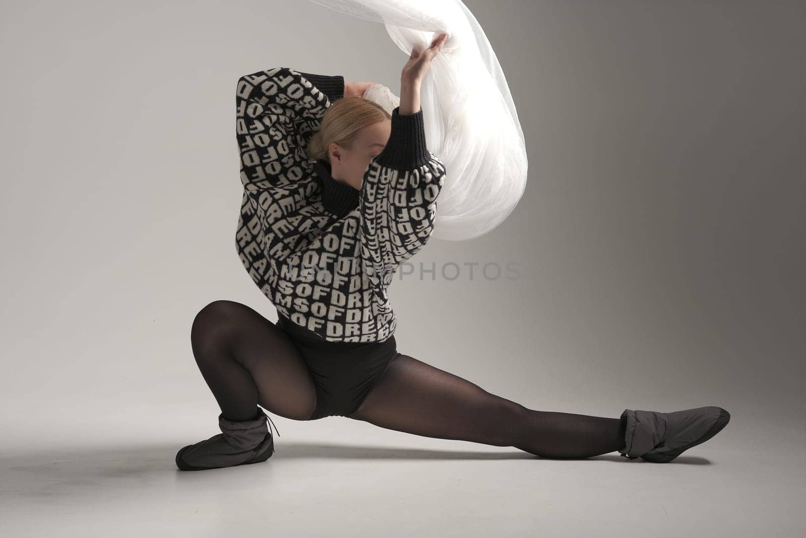 Ballerina Dancing with Silk Fabric, Modern Ballet Dancer with Waving white fabric, Gray Background. With text on sweater DREAMS OF.