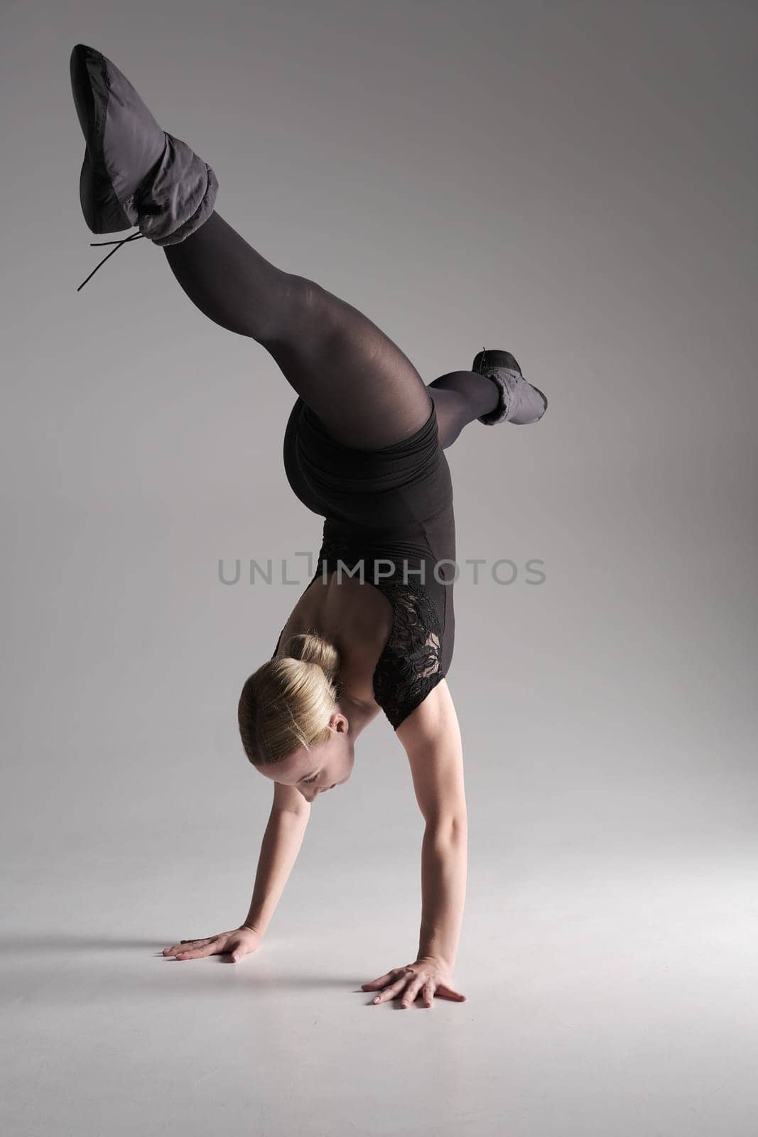 Ballet dancer woman black dress on gray background, Ballerina posing and showing her flexibility on gray background in studio.
