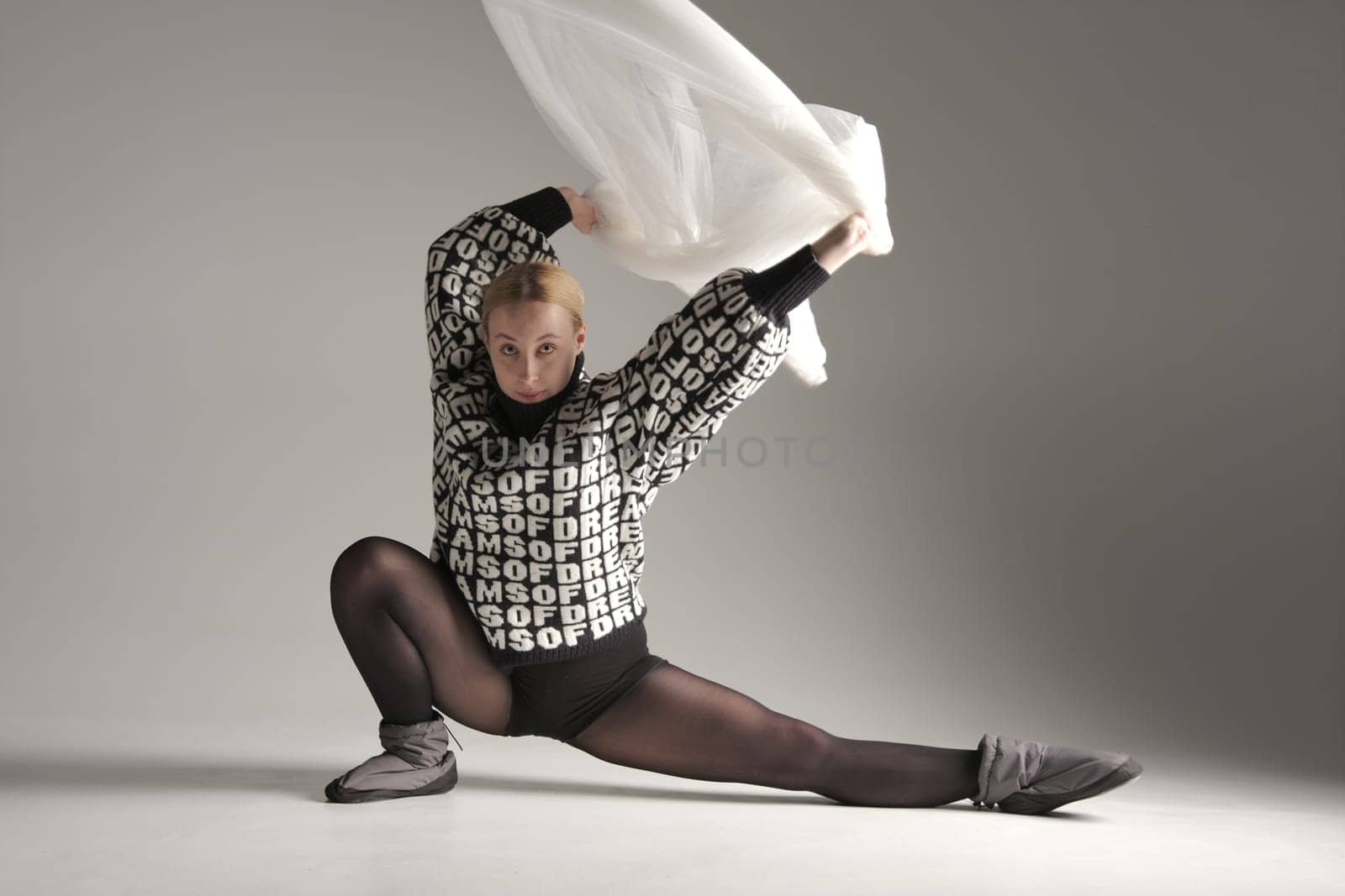 Ballerina Dancing with Silk Fabric, Modern Ballet Dancer with Waving white fabric, Gray Background. With text on sweater DREAMS OF.