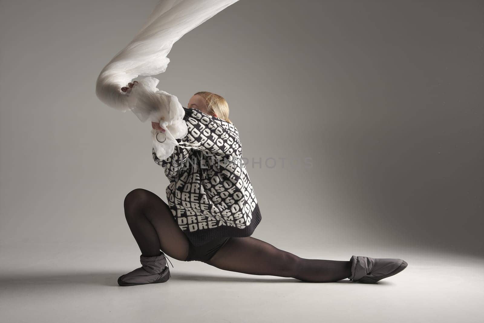 Ballerina Dancing with Silk Fabric, Modern Ballet Dancer with Waving white fabric, Gray Background. With text on sweater DREAMS OF.