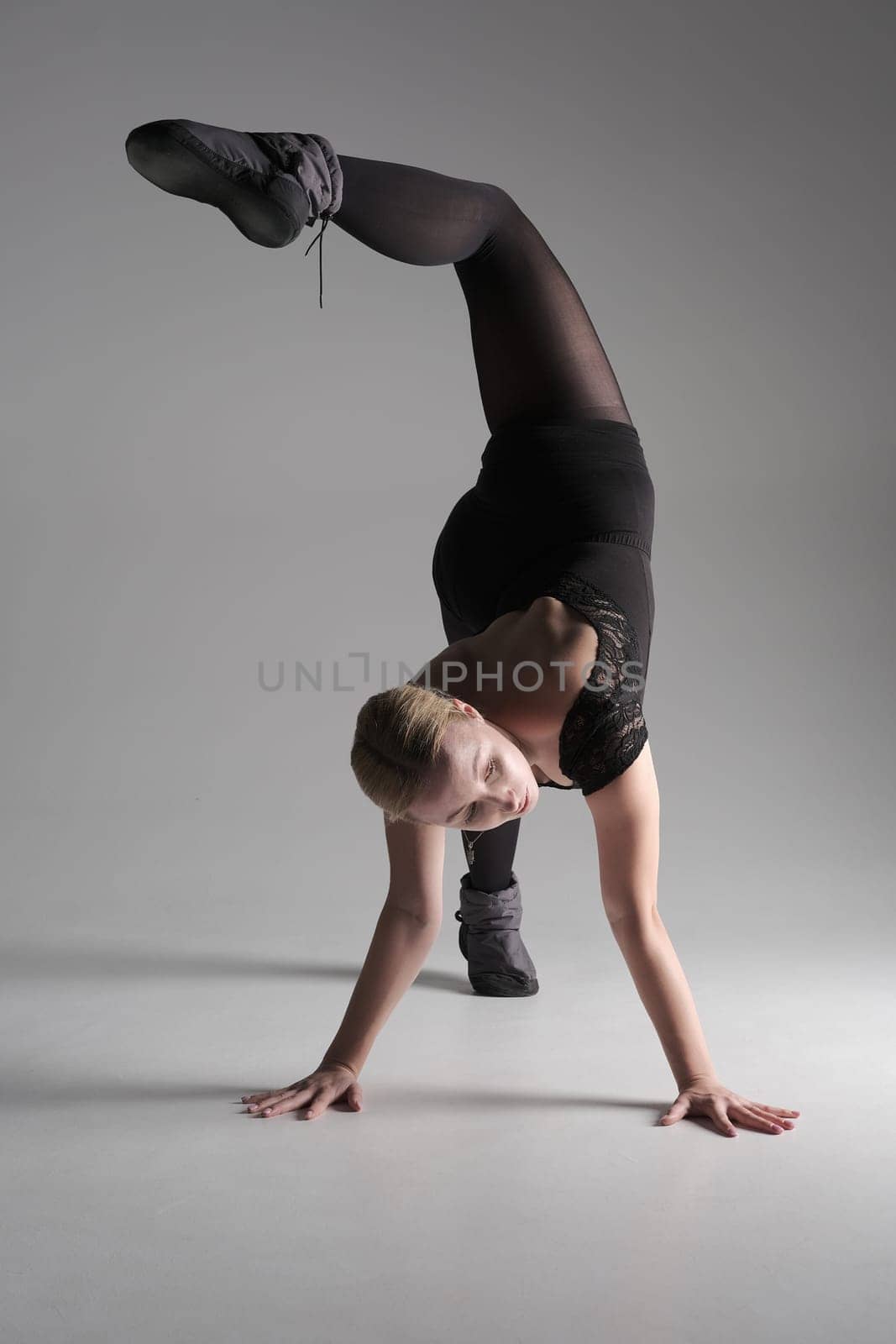 Ballet dancer woman black dress on gray background, Ballerina posing and showing her flexibility on gray background in studio.