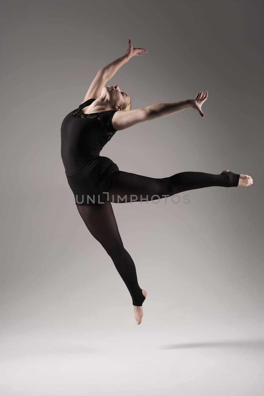 Ballet dancer woman black dress on gray background, Ballerina posing and showing her flexibility on gray background in studio.