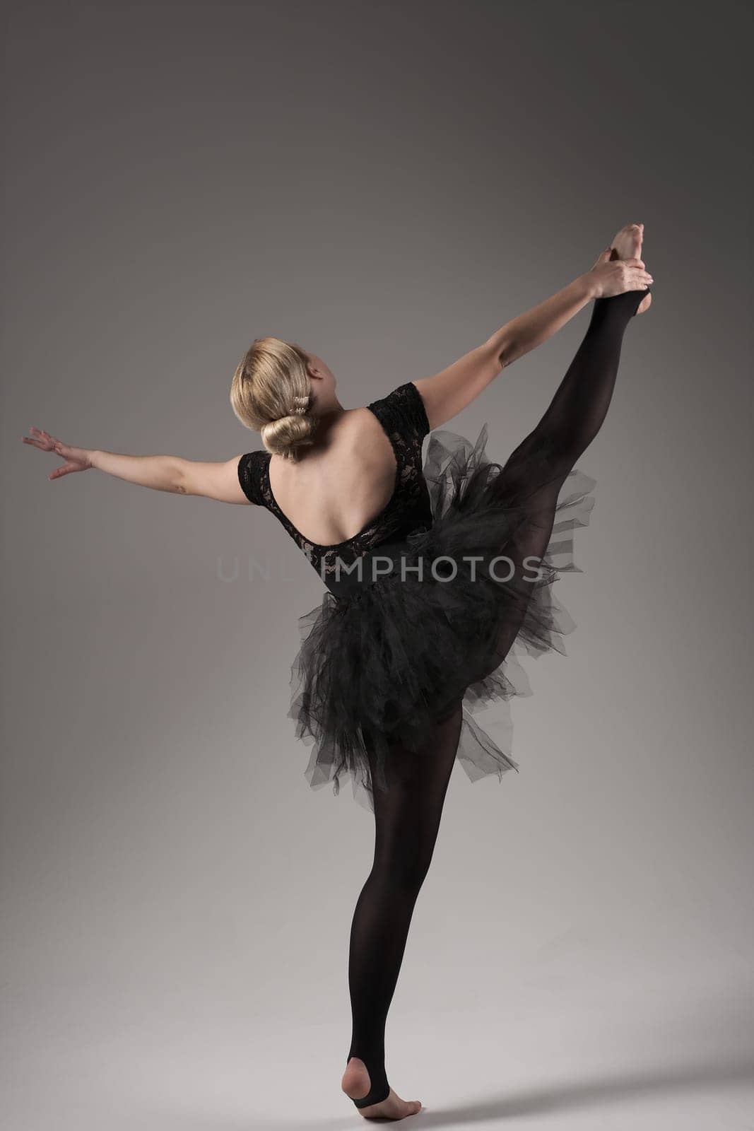 Ballerina Dancing with tutu Modern Ballet Dancer in dancer tutu, Gray Background. Dancer in Black clothes showing her flexibility posing on gray background in studio.