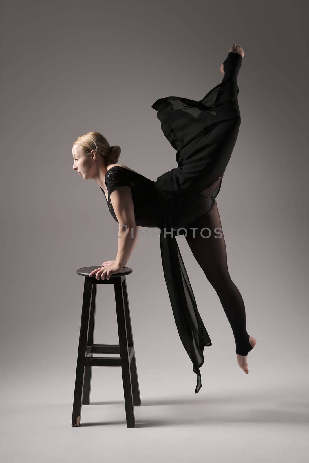 Ballerina Dancing with Silk Fabric, Modern Ballet Dancer in Fluttering Waving Cloth, Gray Background with black chair.