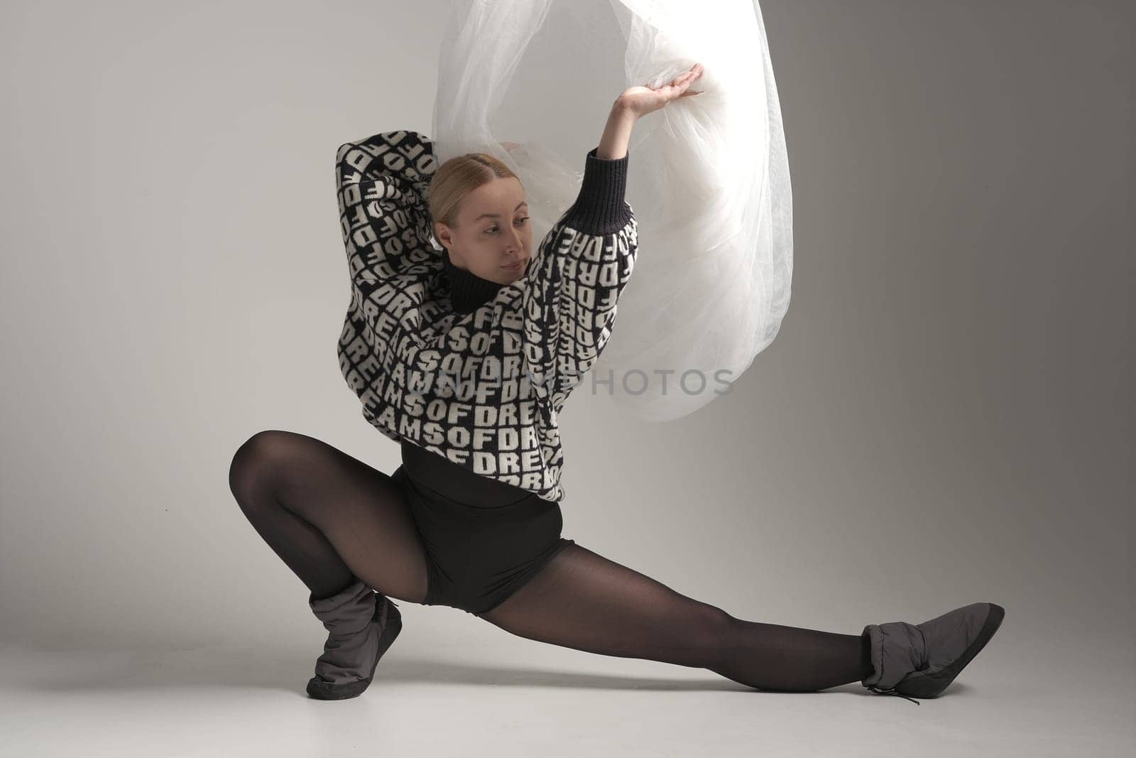 Ballerina Dancing with Silk Fabric, Modern Ballet Dancer with Waving white fabric, Gray Background. With text on sweater DREAMS OF.