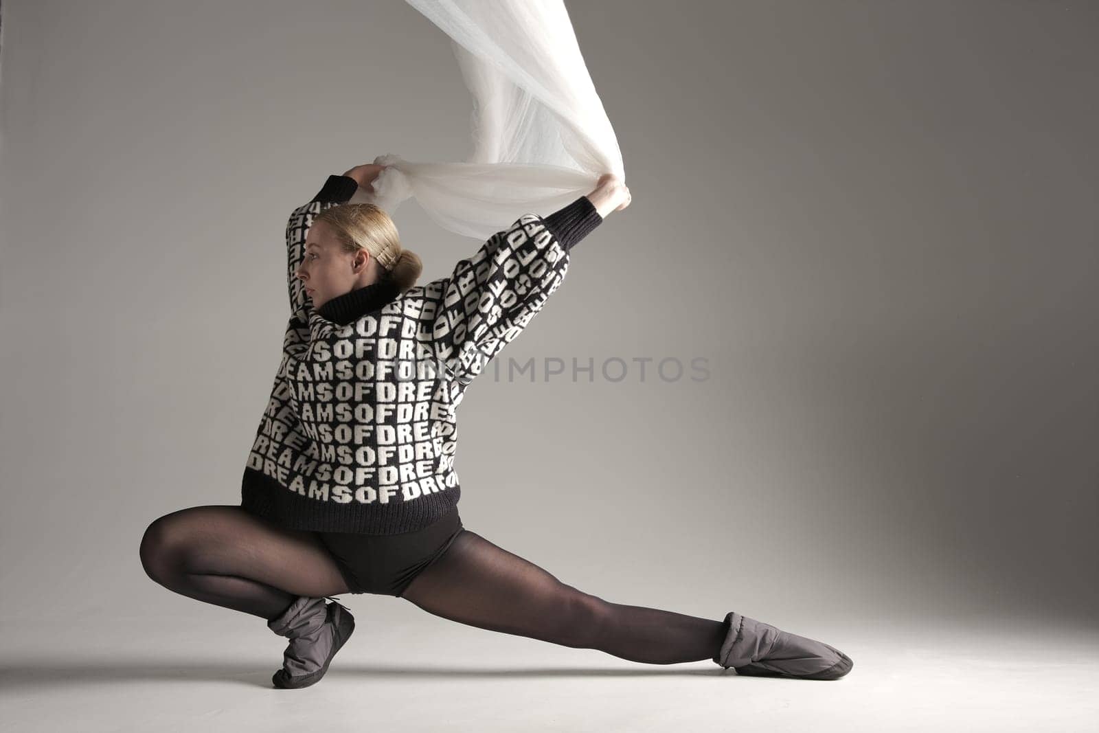 Ballerina Dancing with Silk Fabric, Modern Ballet Dancer with Waving white fabric, Gray Background. With text on sweater DREAMS OF.