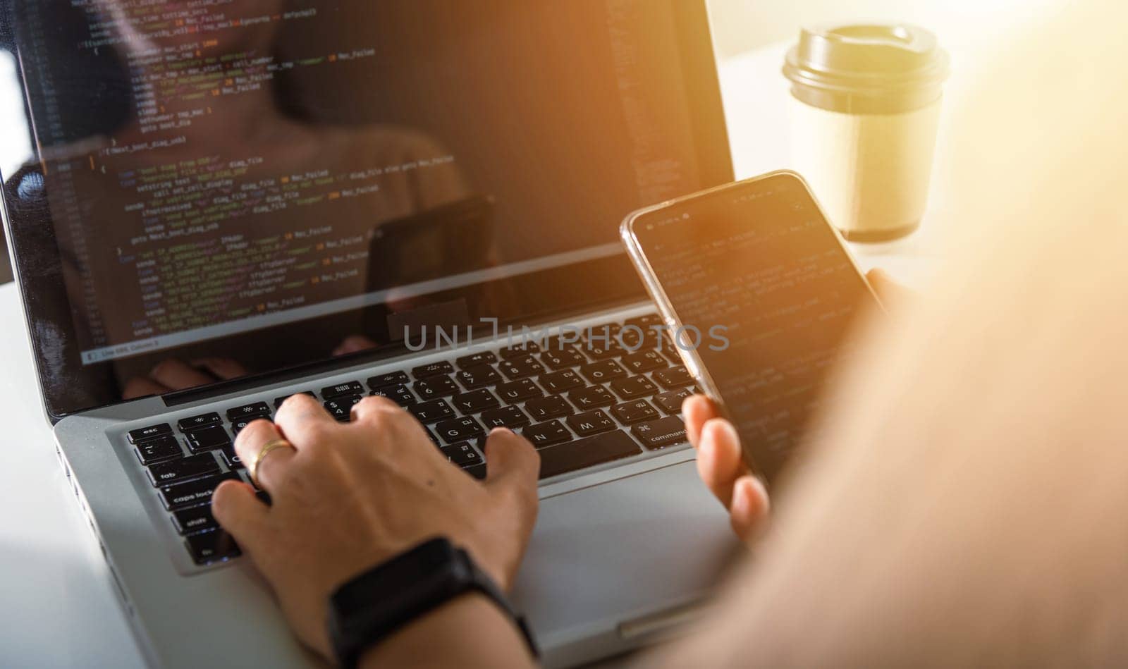 Software developer hands typing data coding programming javascript with laptop computer and mobile phone, Programmer woman looking smartphone program code at workplace, IT startup concept