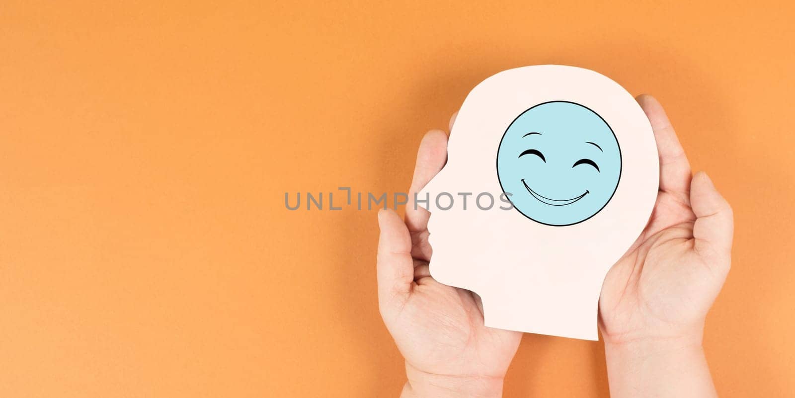Holding a head with a happy smiling face, mental health concept, positive mindset, support and evaluation symbol