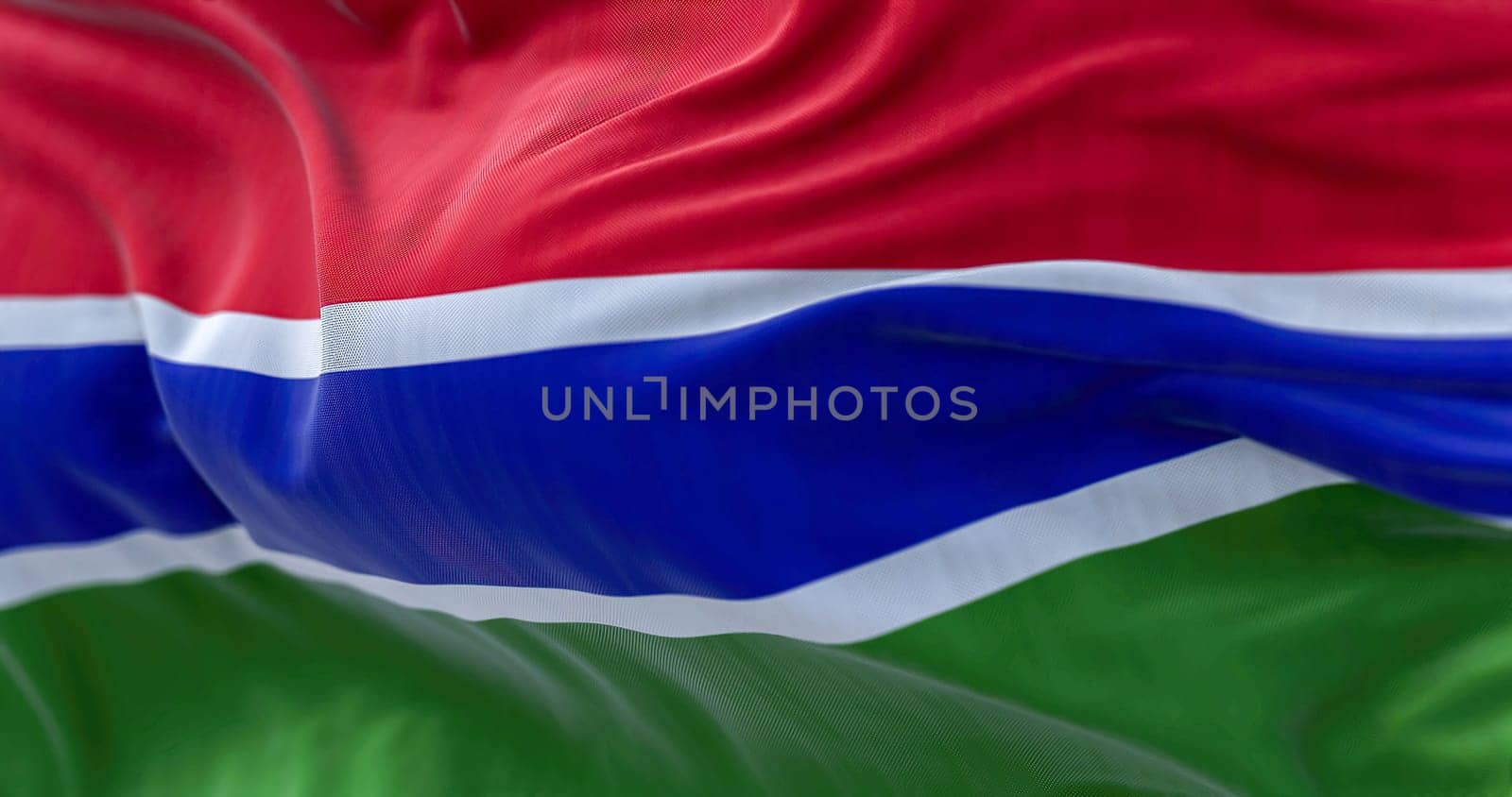 Close-up view of the Gambia national flag waving in the wind. The Republic of the Gambia is a West African state. Fabric textured background. Selective focus