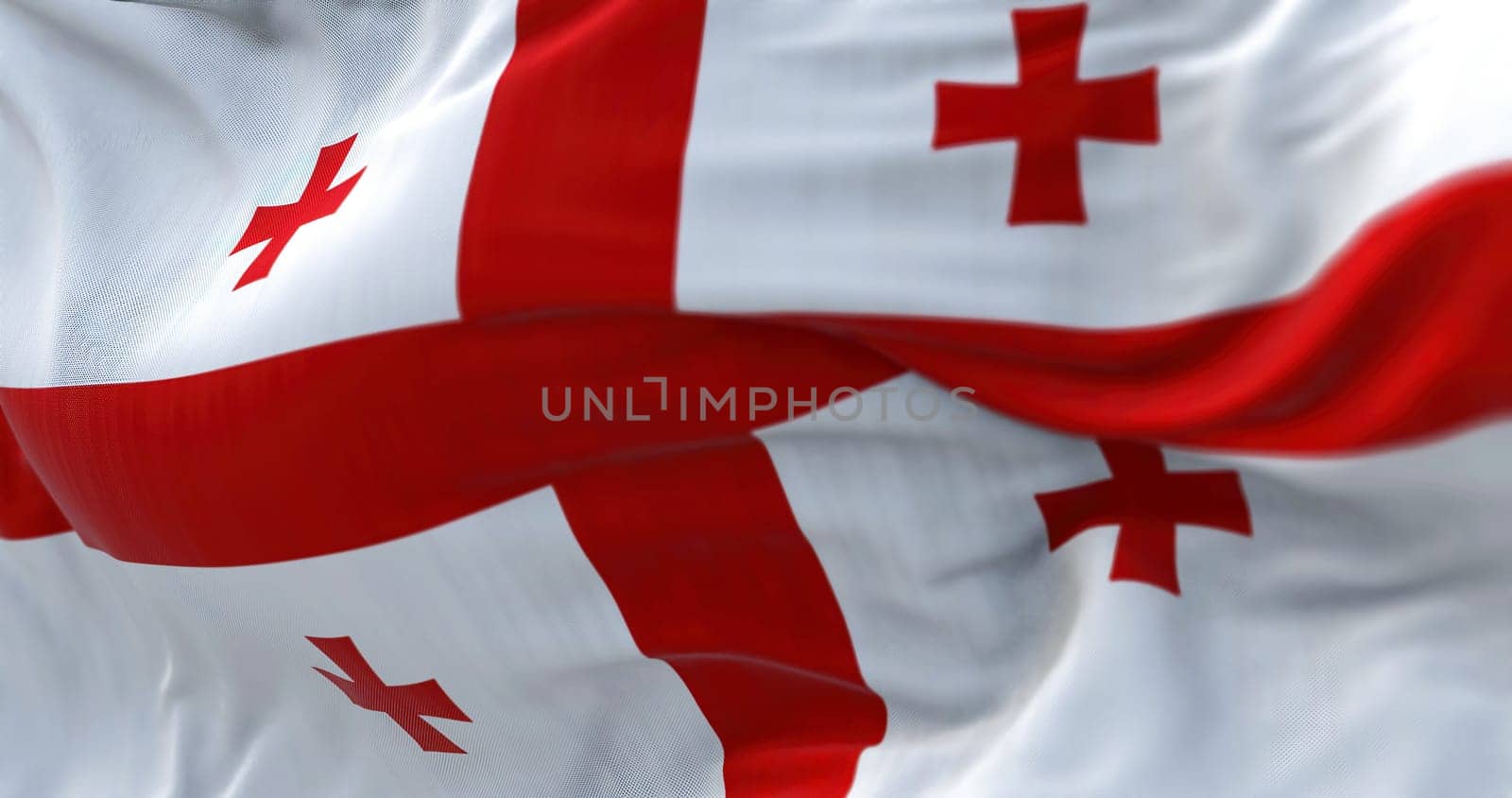 Close-up view of the Georgian national flag waving in the wind. Georgia is a country at the intersection of Eastern Europe and Western Asia. Fabric textured background. Selective focus