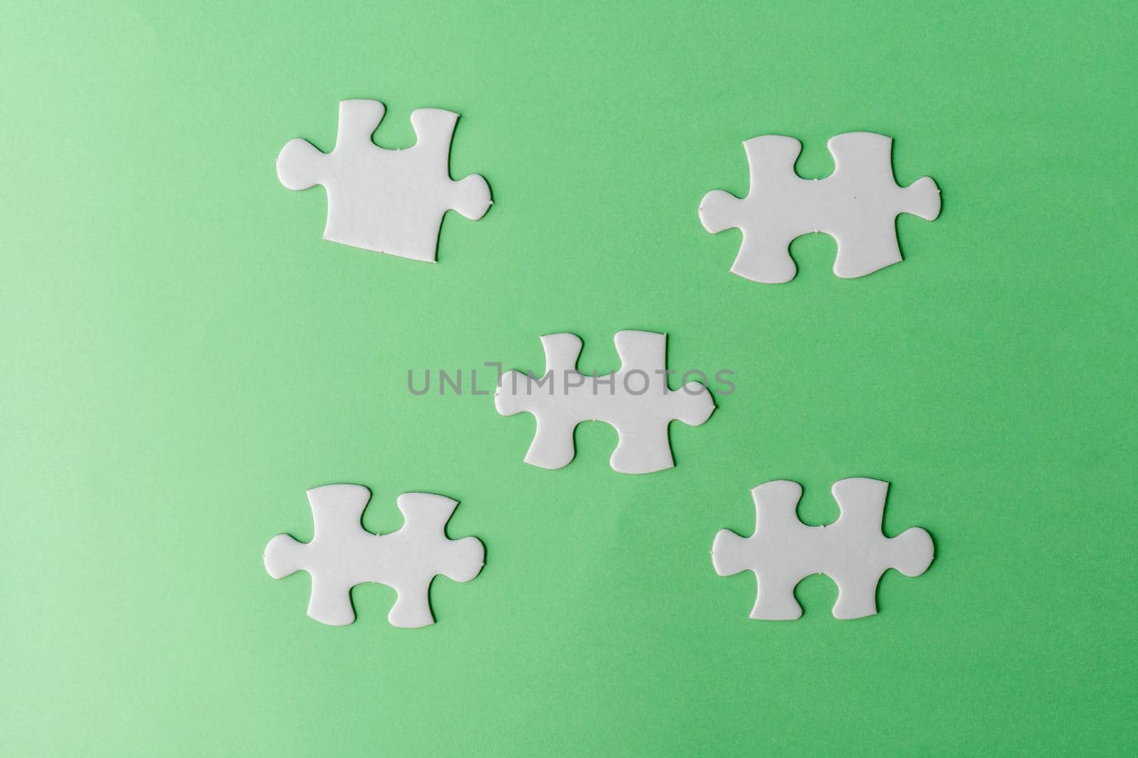 Pieces of white jigsaw puzzle on green background