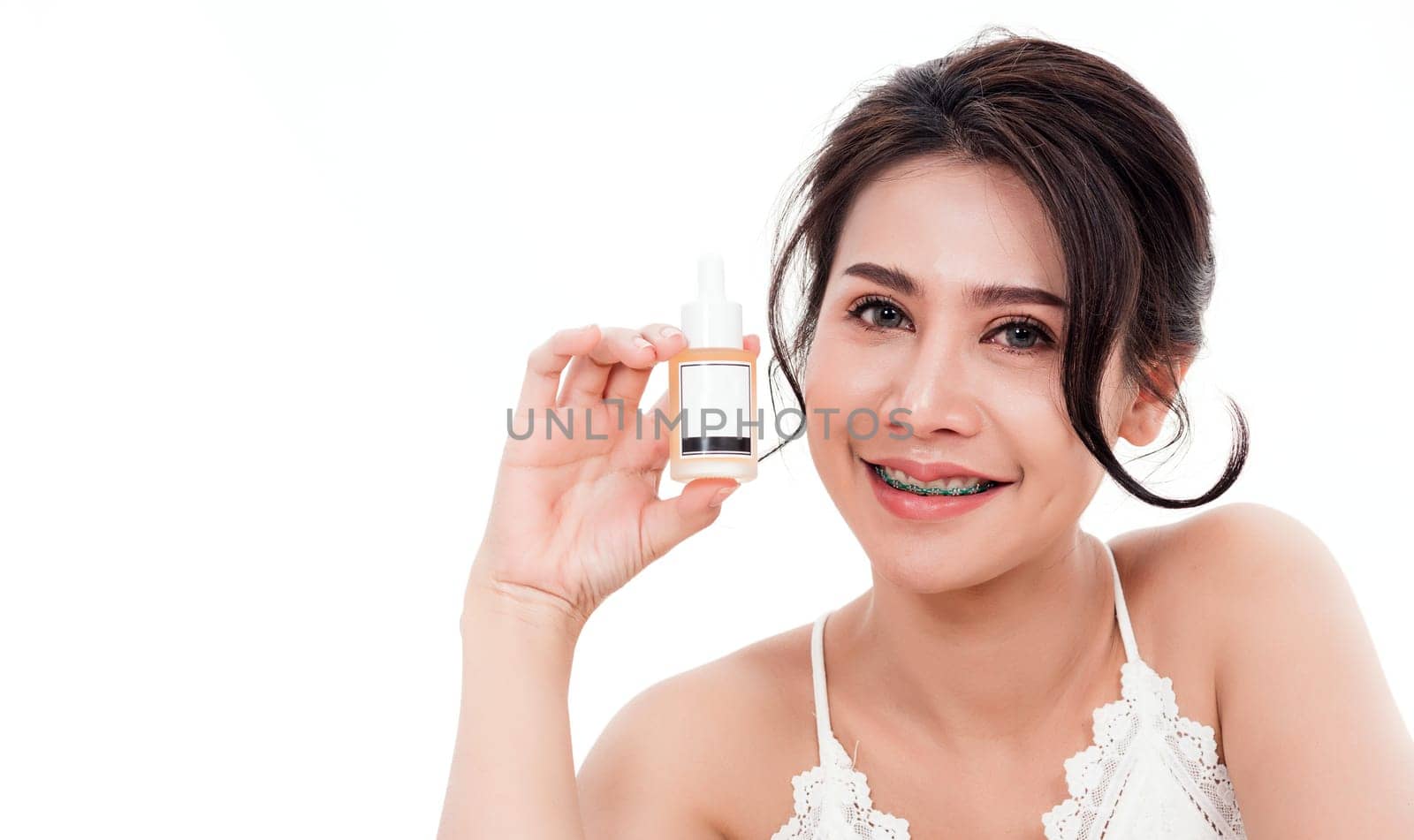 Asian young beautiful woman smiling she's holding bottle serum hair or skin care near face for present product isolated on over white background, Beauty salon concept