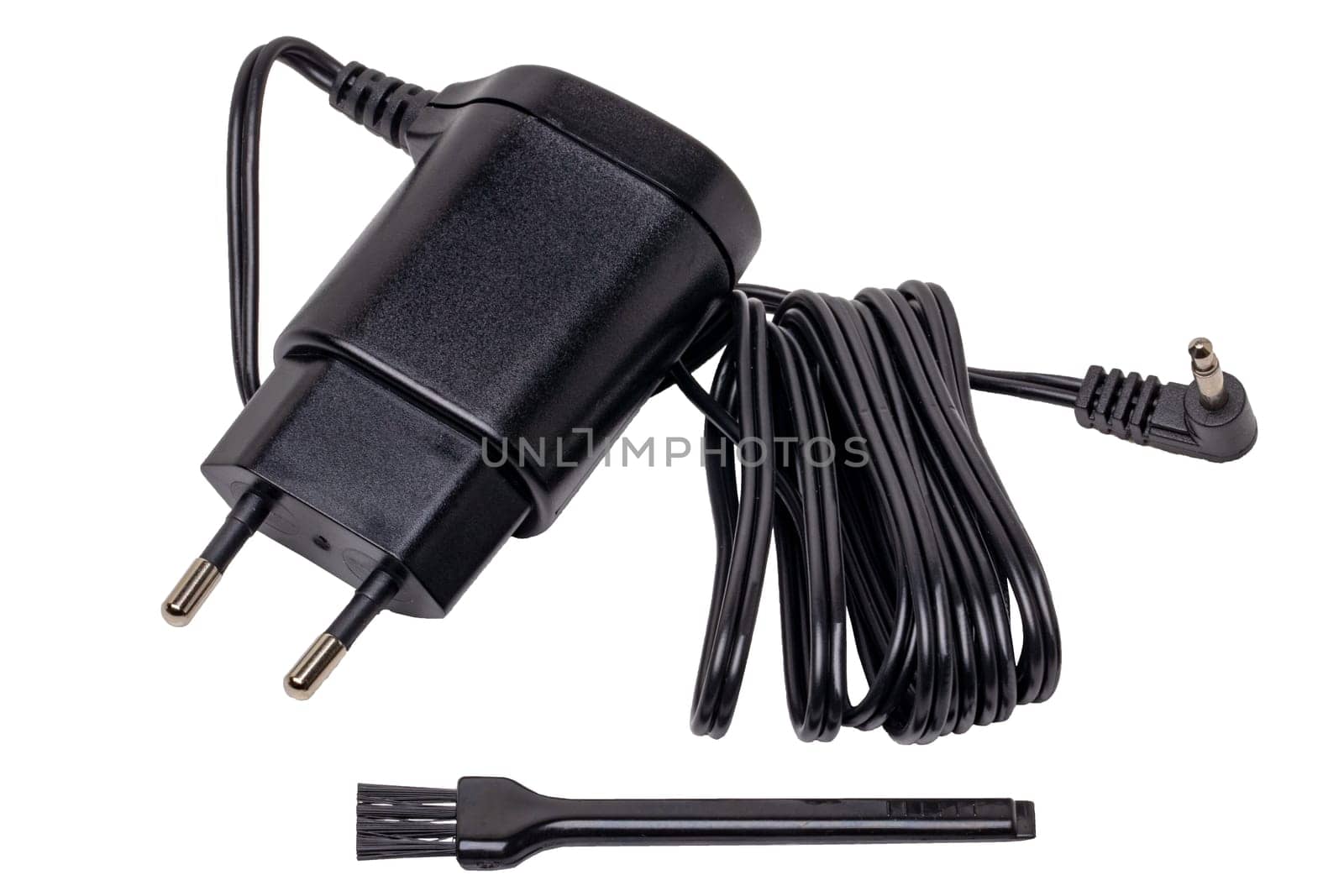 Closeup of a black AC to DC power adapter or charger for a rechargeable beard and hair clipper and a cleaning brush isolated on white background. Macro.
