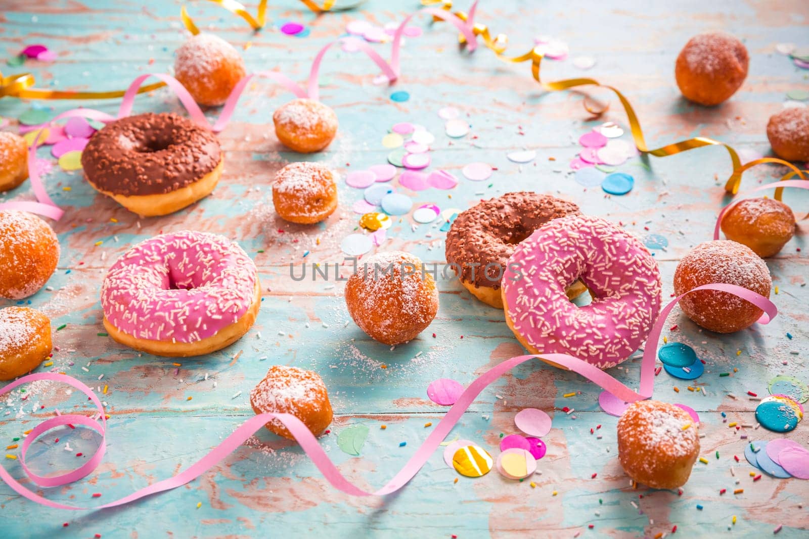 Traditional Berliner for carnival and party. German Krapfen or donuts with streamers and confetti. Colorful carnival or birthday image