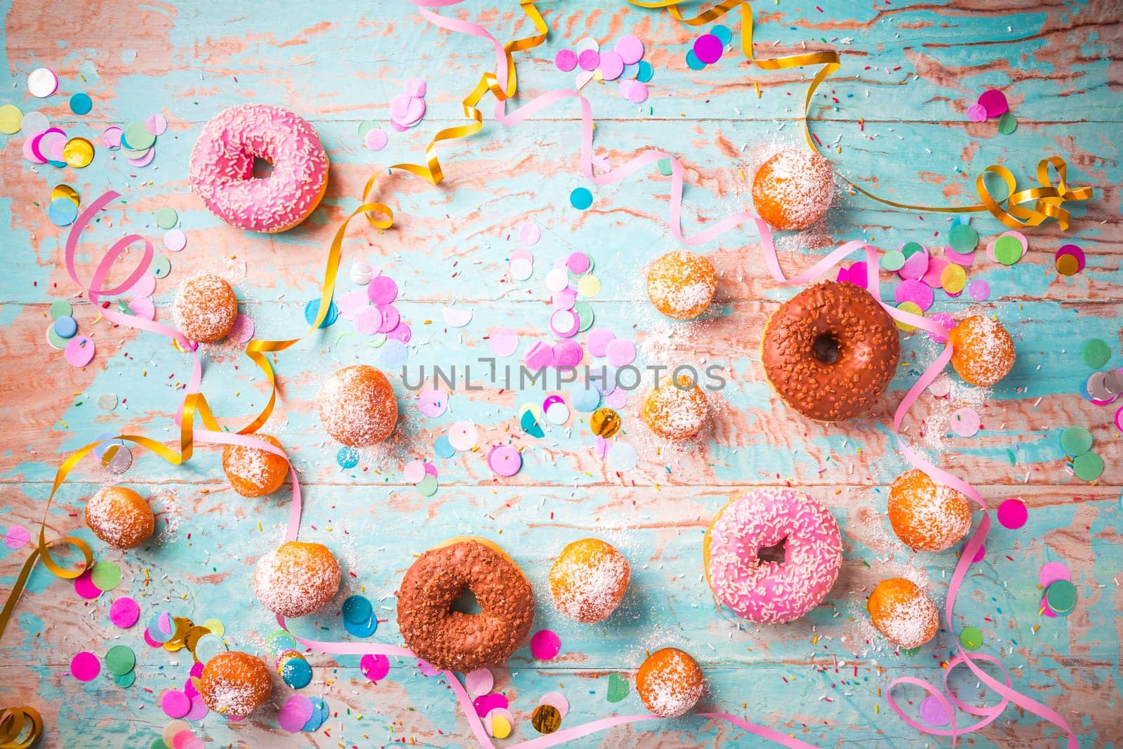 Traditional Berliner for carnival and party. German Krapfen or donuts with streamers and confetti. Colorful carnival or birthday image