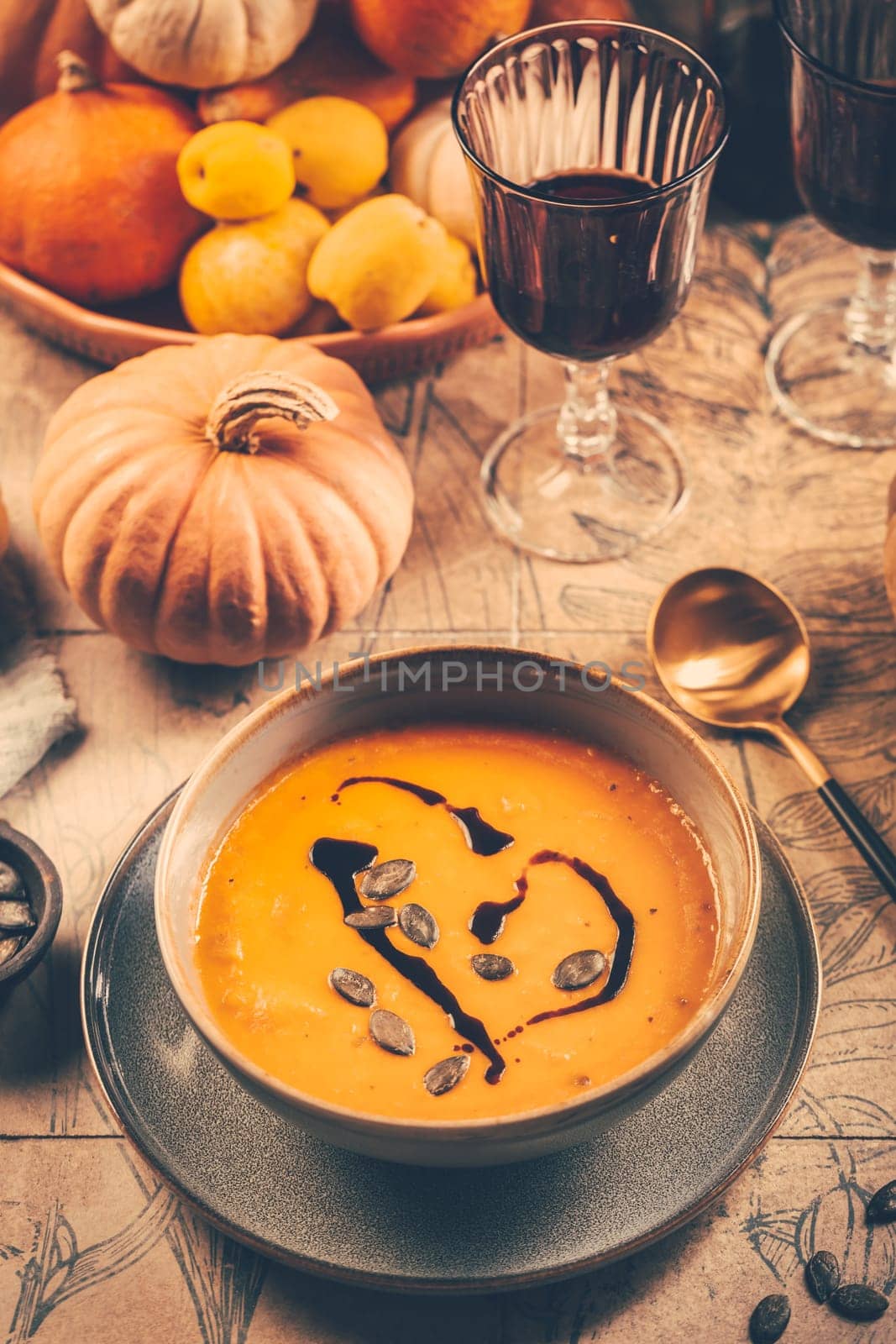 Pumpkin cream soup with pumpkin seeds on decorated kitchen table