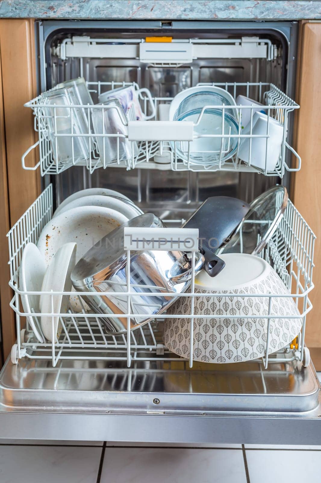 Open modern dishwasher with messy dishes in the kitchen, built-in kitchen dish washing machine