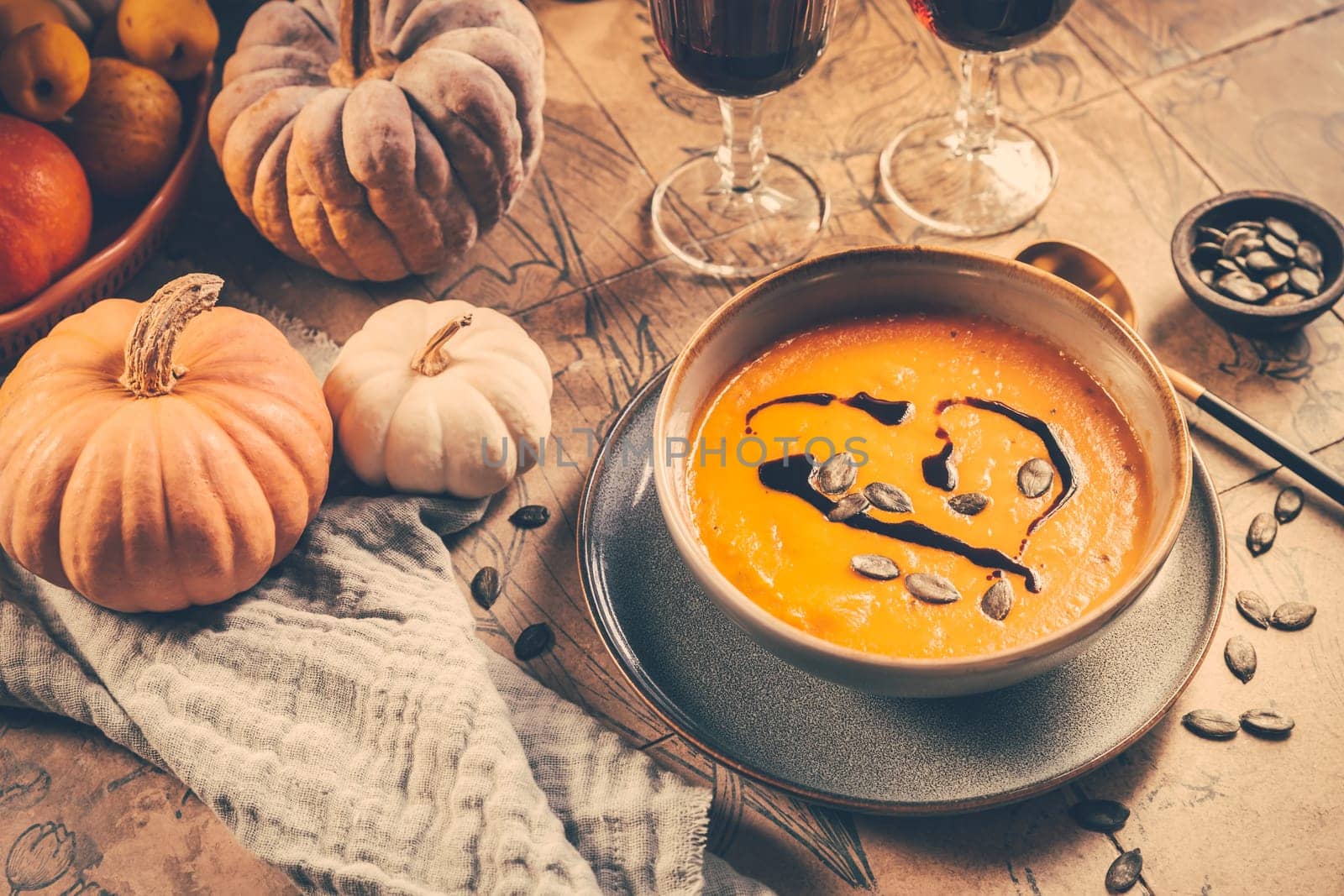 Pumpkin cream soup with pumpkin seeds on decorated kitchen table