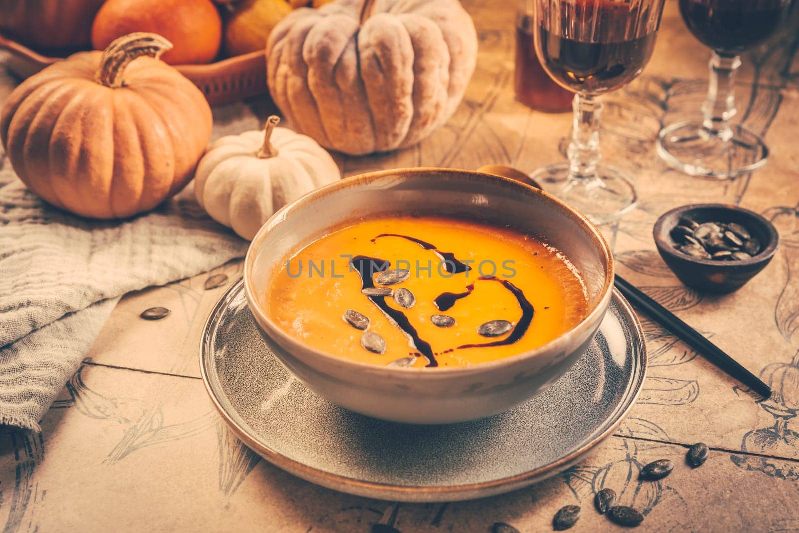 Pumpkin cream soup with pumpkin seeds on decorated kitchen table