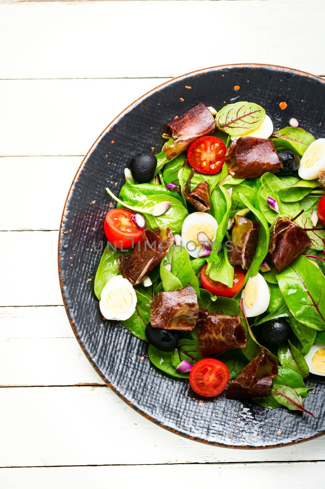 Appetizing salad with fresh herbs, raw vegetables and bacon
