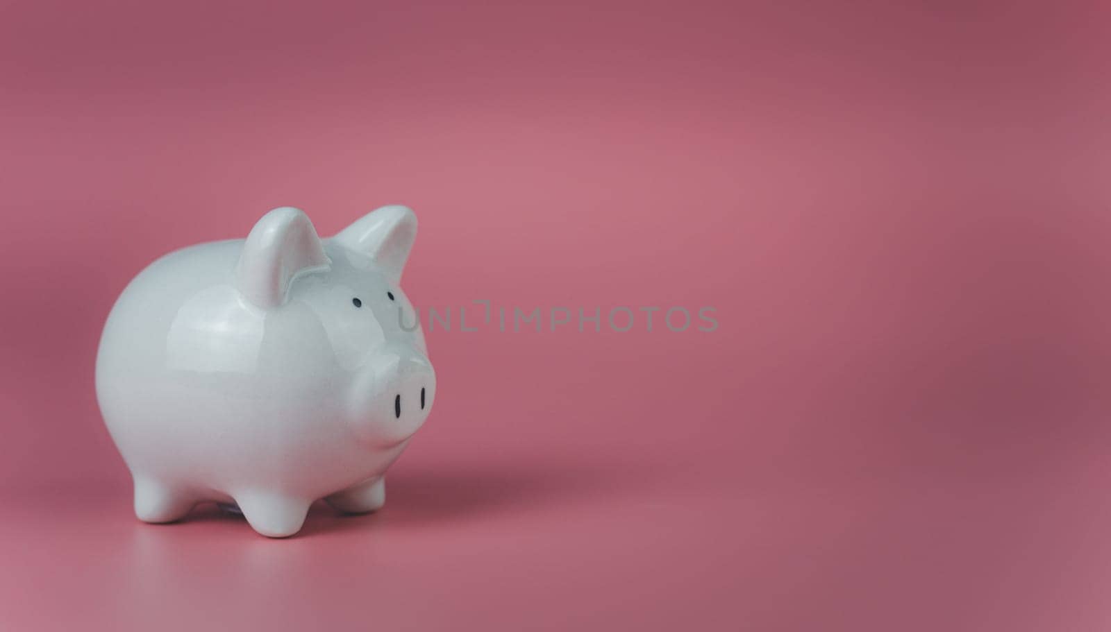 white piggy bank on a pink background. Savings and investment concepts.
