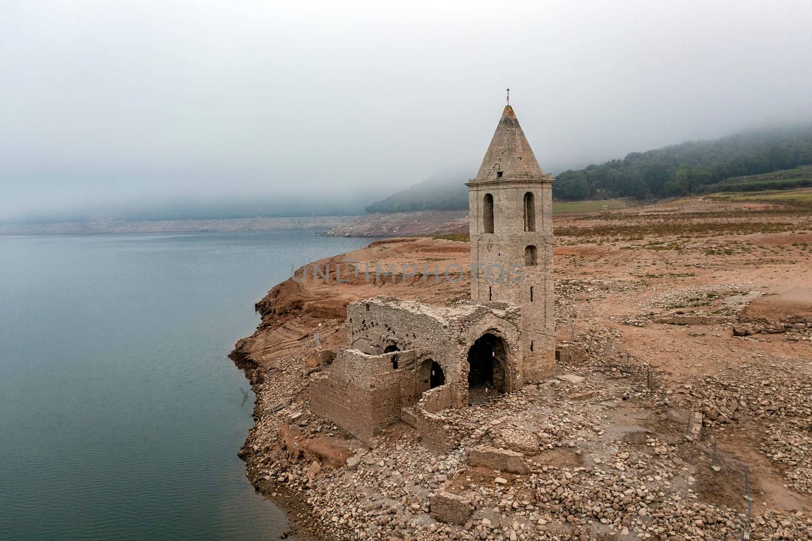Aerial view of Sau Reservoir, in the Ter River, in the Province of Girona, Catalonia, Spain. After months without rain the level of the swamp is very low. Detail of the church of Sant Roma