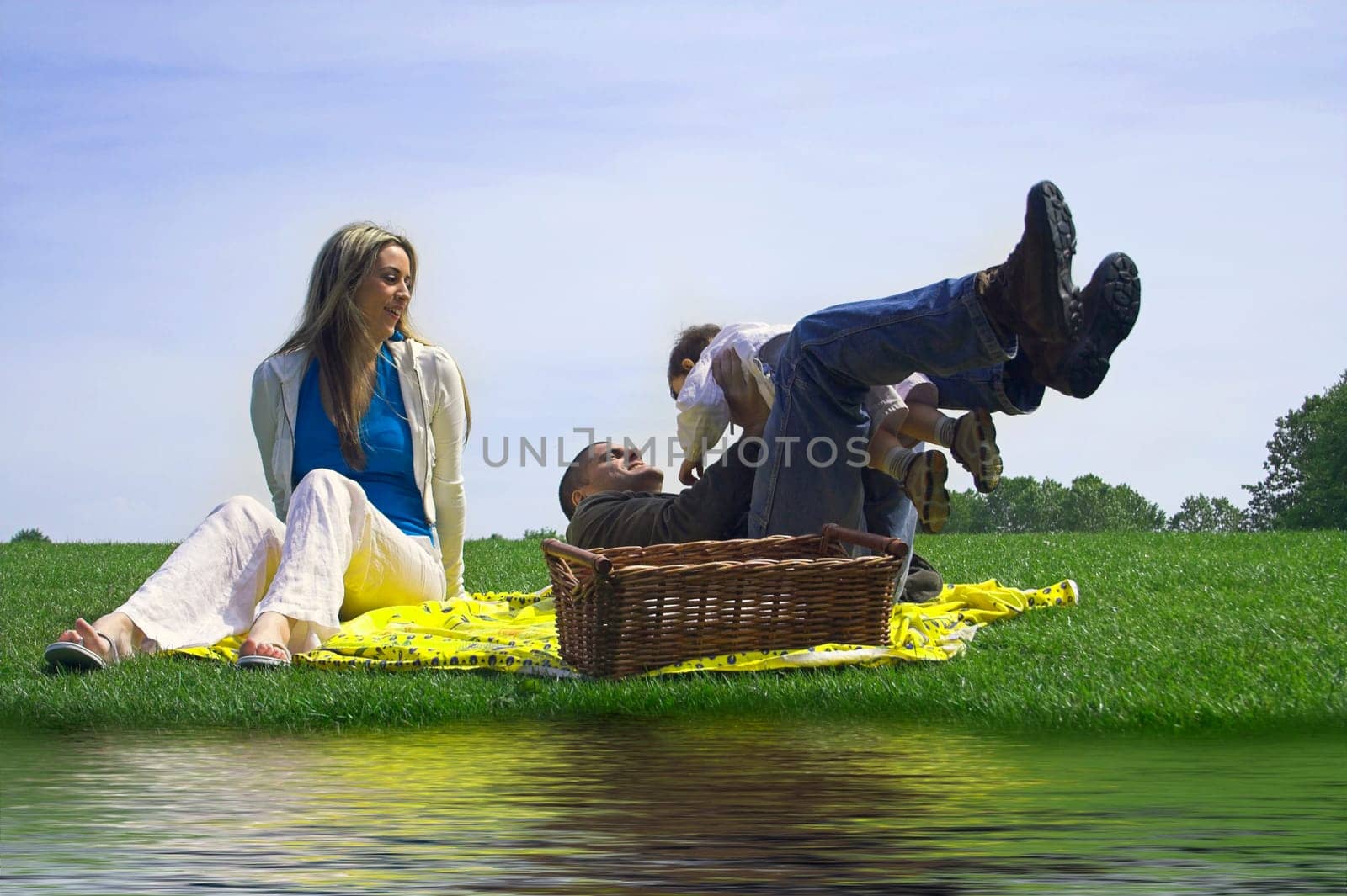 family outdoor in a field near water having a pick nick