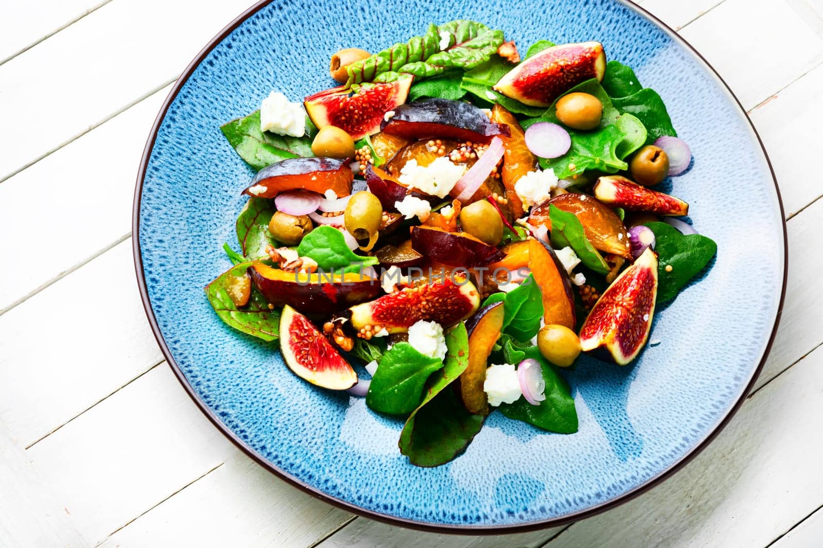 Unusual salad with figs, plums, herbs and olives. Natural salad