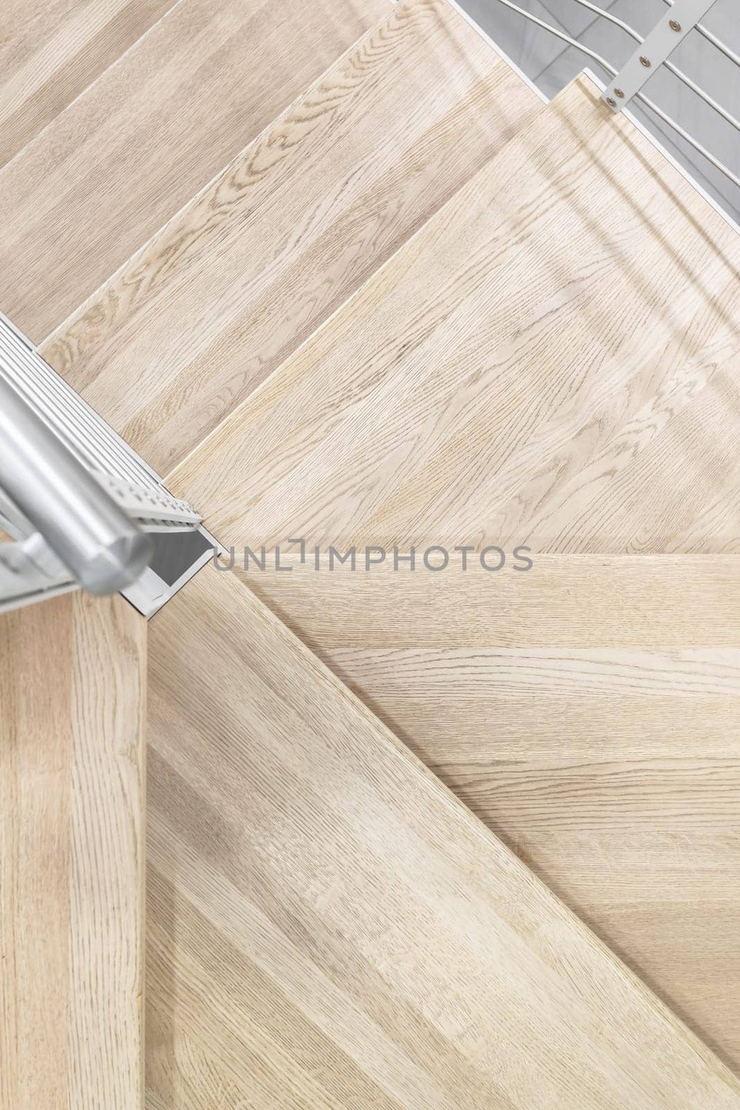 Close-up detail view of natural wooden stair steps. Metal handrail.