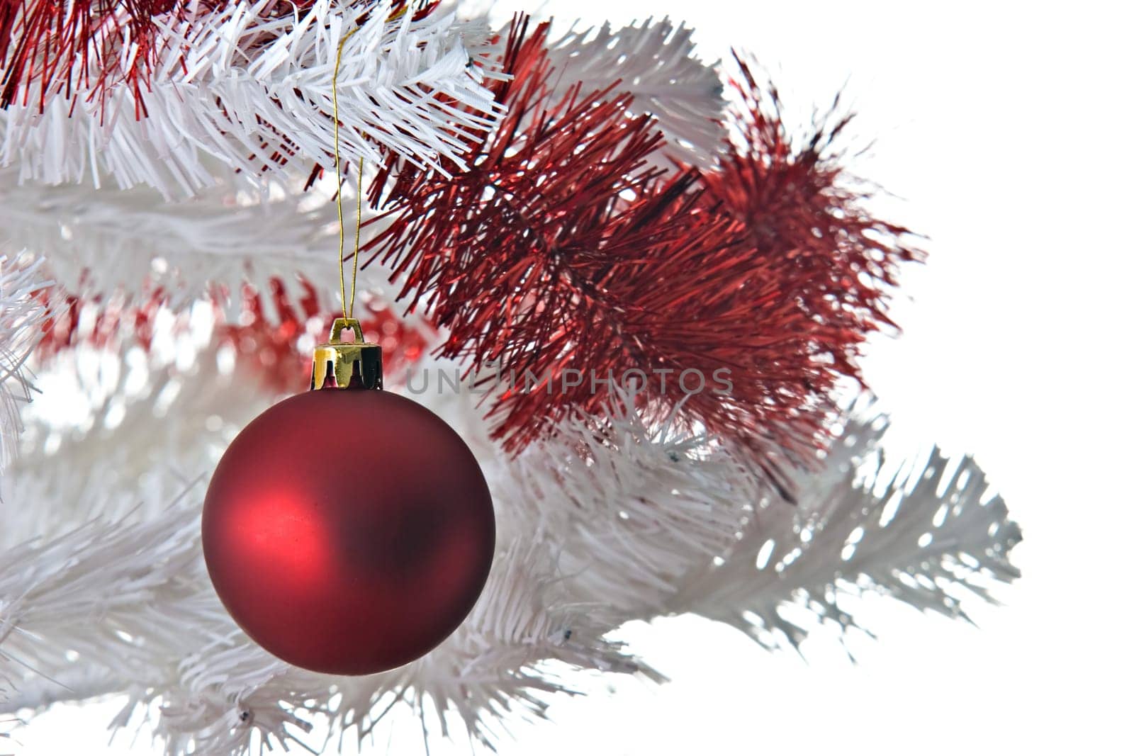 Red christmas ball and ribbon on a white christmas tree.