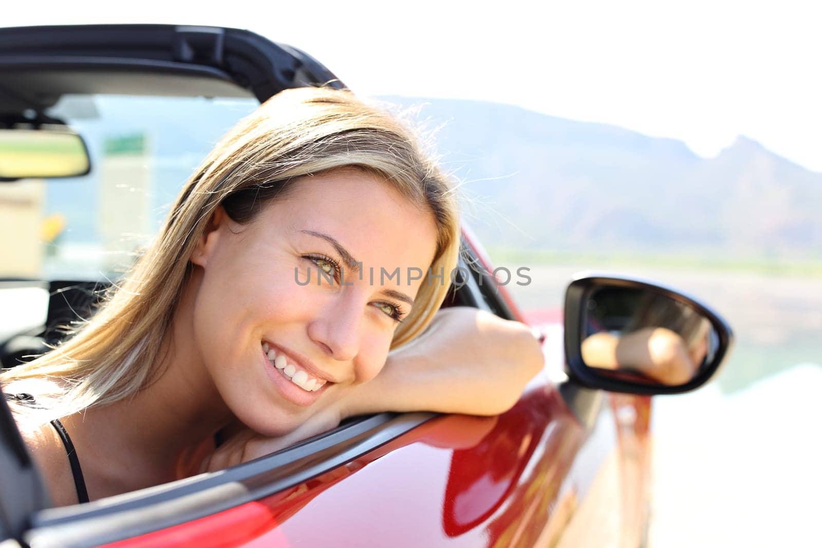 Happy convertible car driver smiling and resting looking away