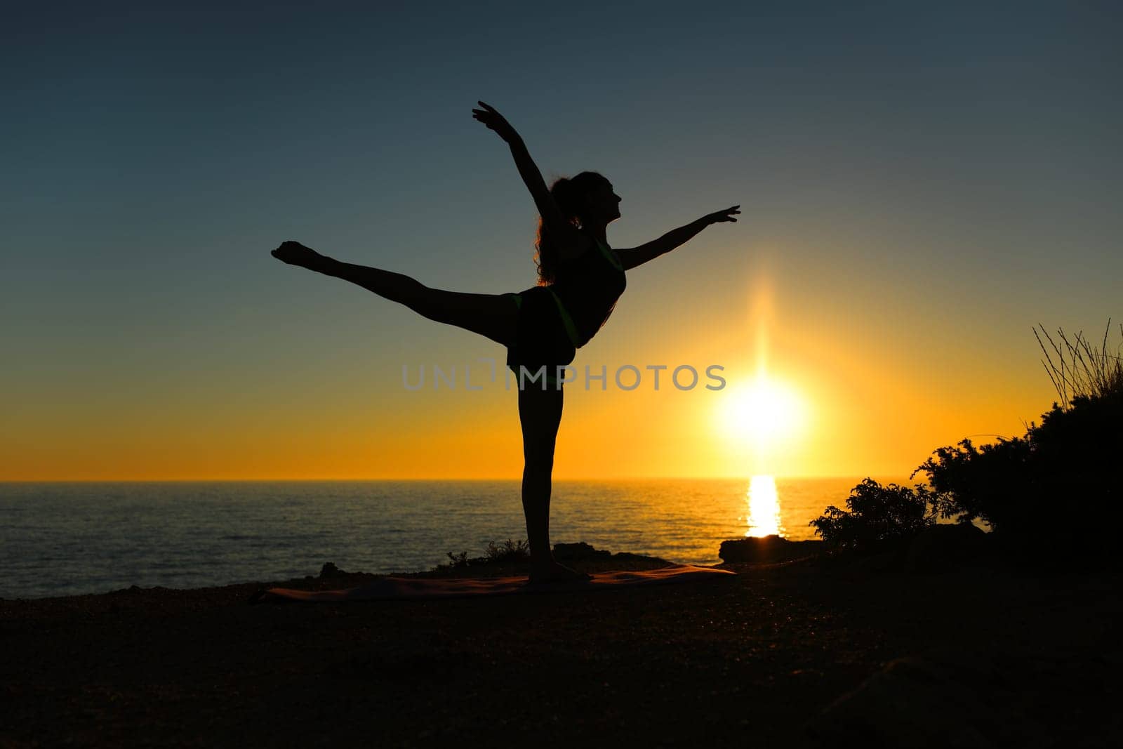 Woman silhouette dancing ballet at sunset on the beach
