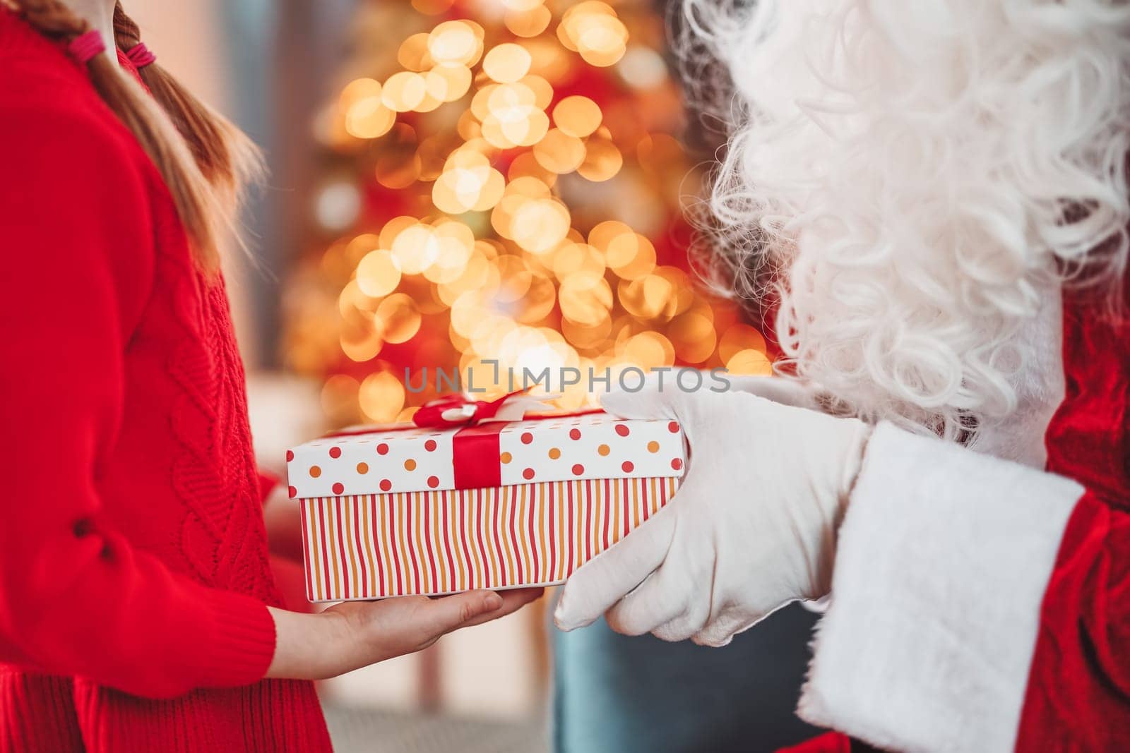 Hands of Santa Claus giving giftbox to the child. Concept of Christmas and New Year.